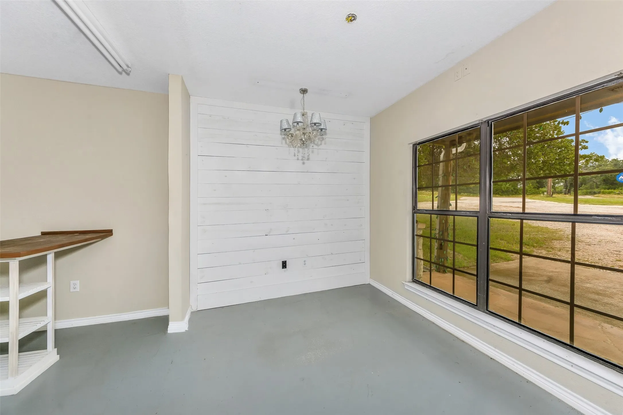 Interior space featuring a white shiplap accent wall, a crystal chandelier, and a large multi-pane window