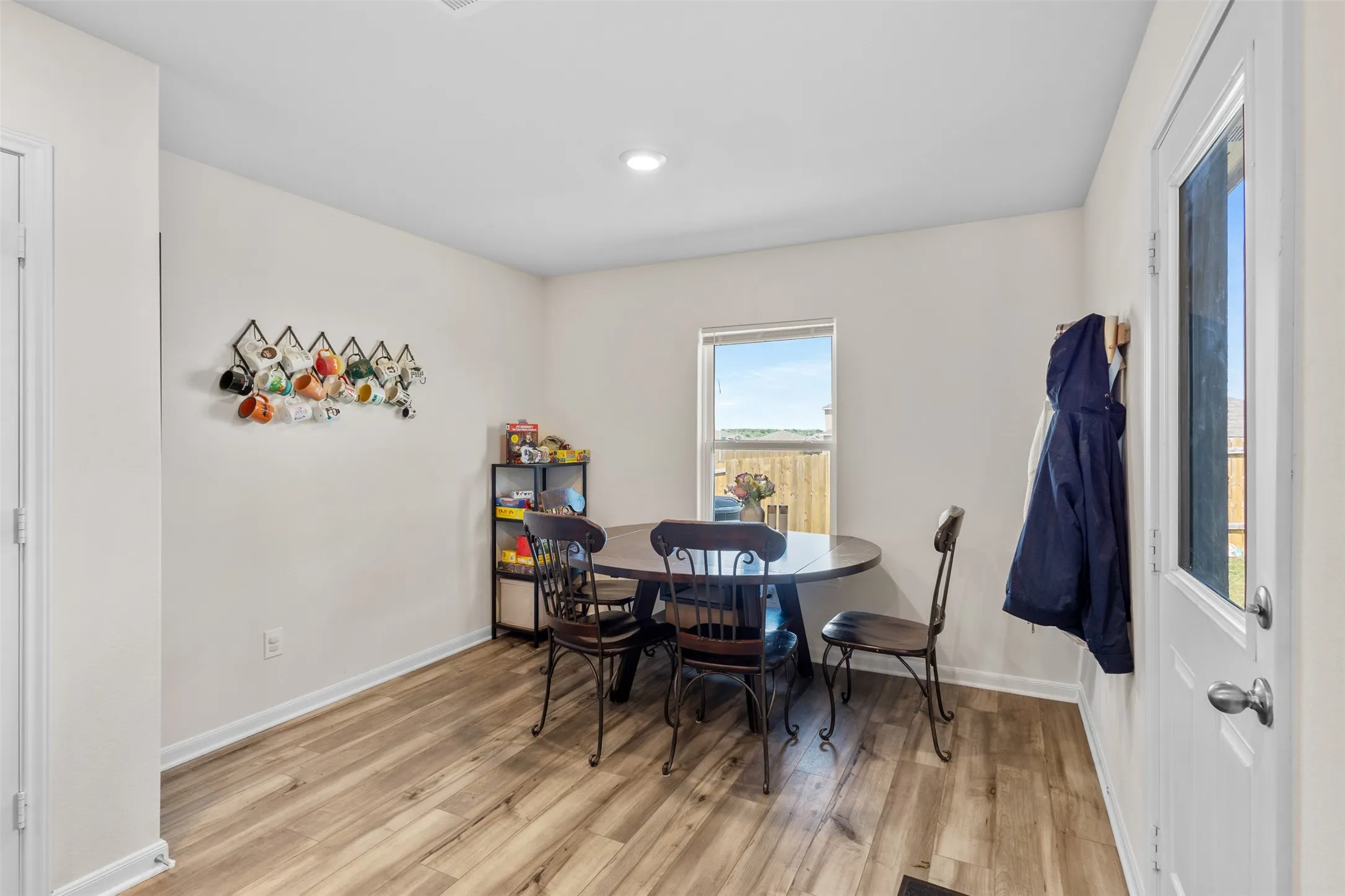 Dining area featuring wood-finish flooring, a window offering natural light, and a white paneled door with a full-lite window