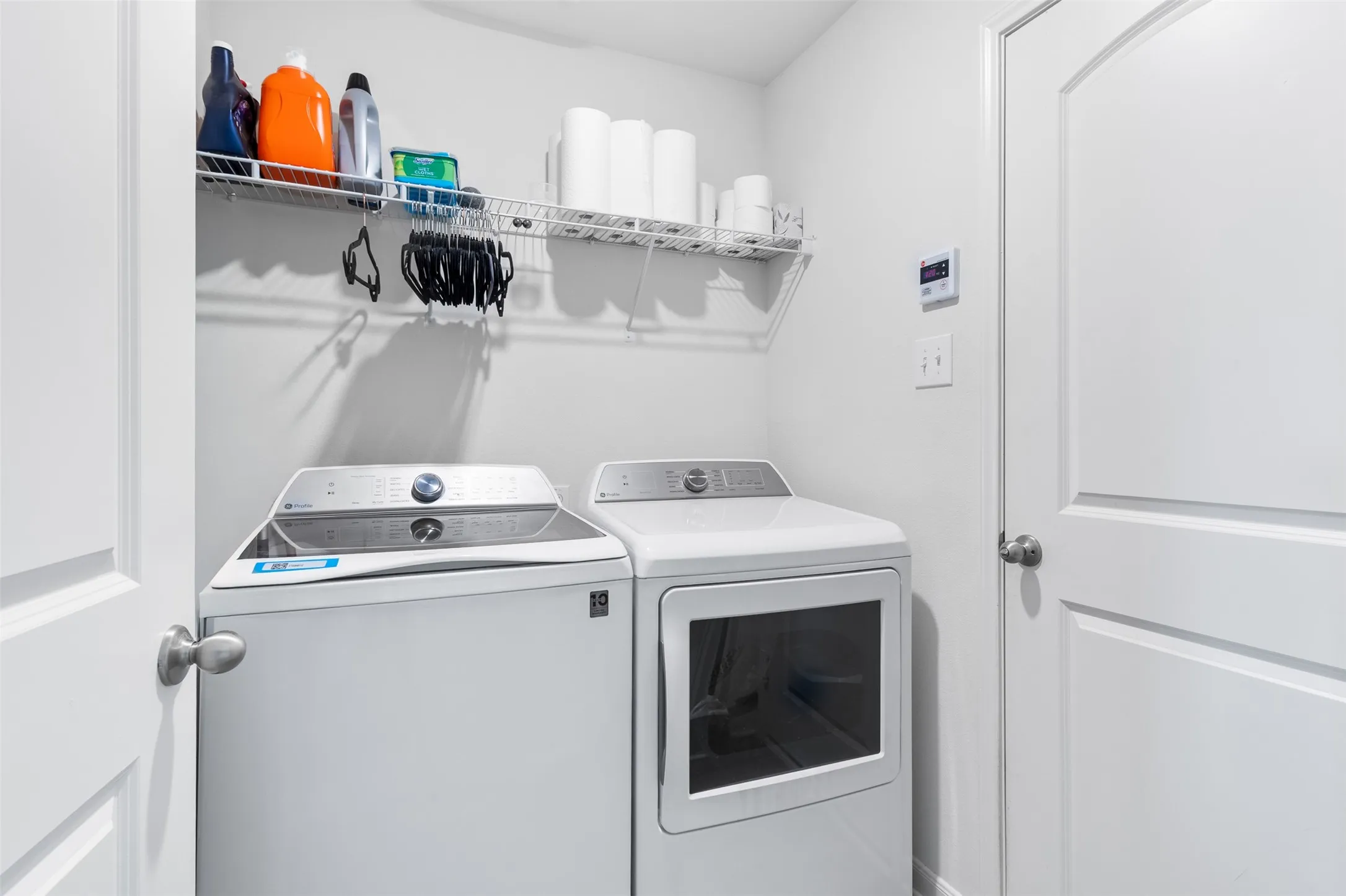 Dedicated laundry area featuring a wire rack shelving system and light gray wall paint