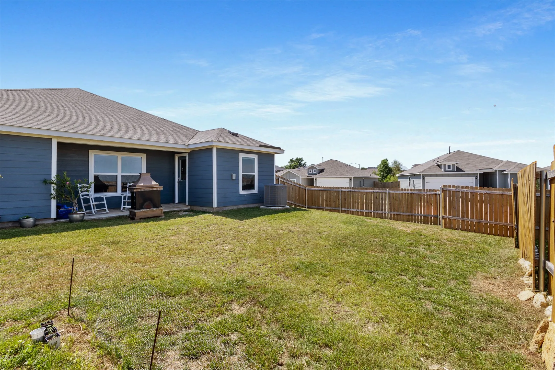 Expansive backyard featuring a manicured lawn, a full wood privacy fence, and a concrete patio
