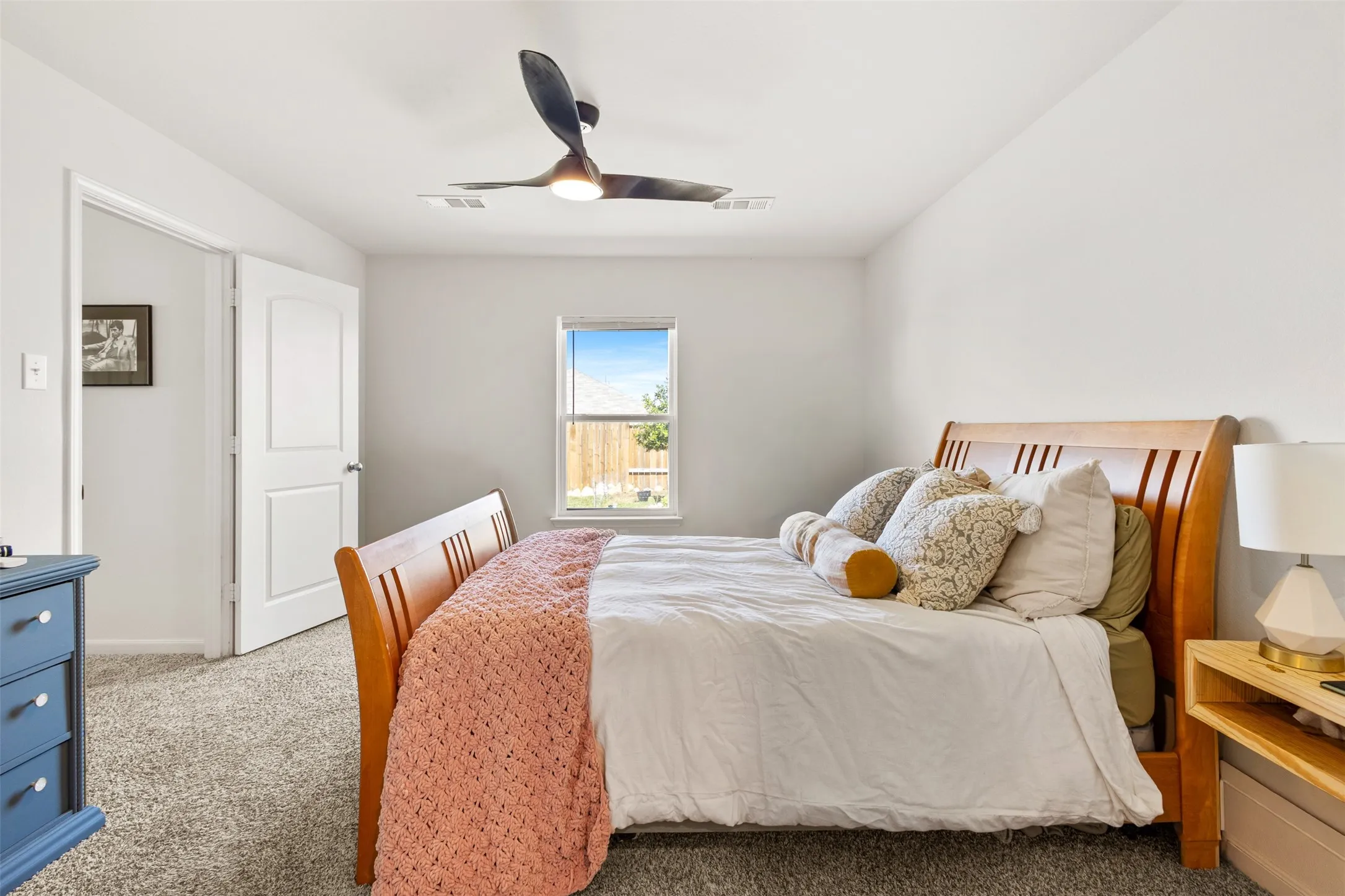 Carpeted room with a modern ceiling fan, a window providing natural light, and a white interior door