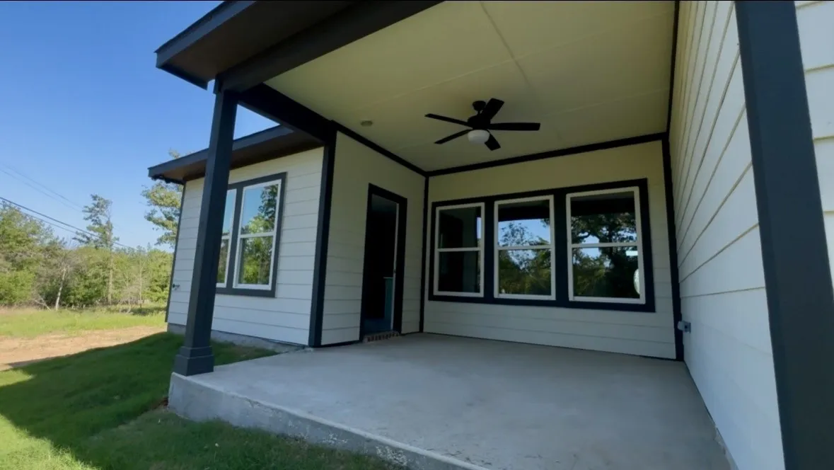Covered outdoor patio  black ceiling fan, and multiple exterior windows