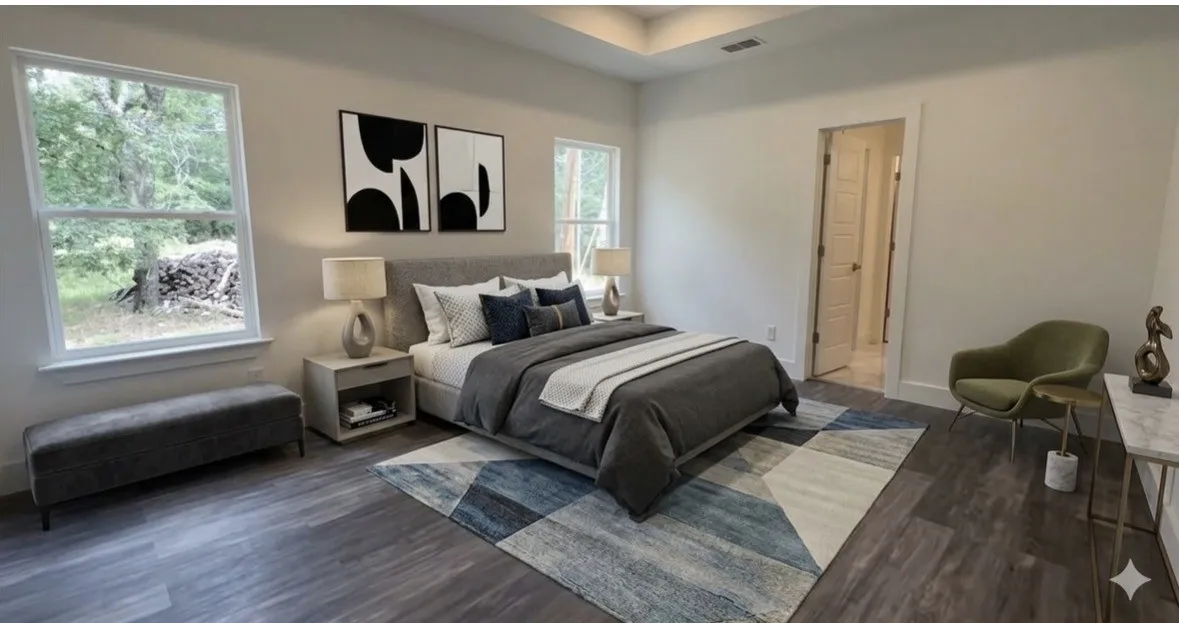 Spacious bedroom featuring wood-finish flooring, two large windows, a tray ceiling, and a doorway