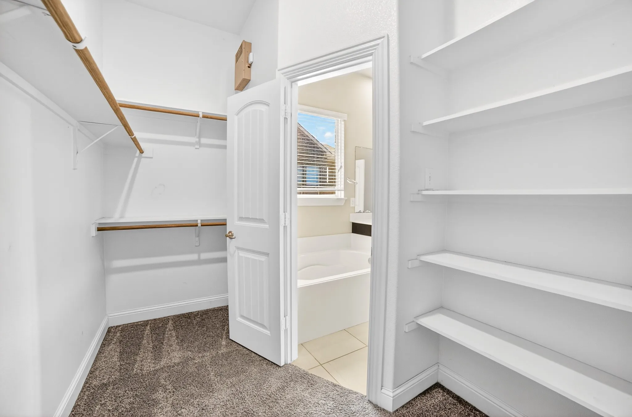 Huge master closet with lbuilt-in organizer shelves and shelves over all clothes hanging bars