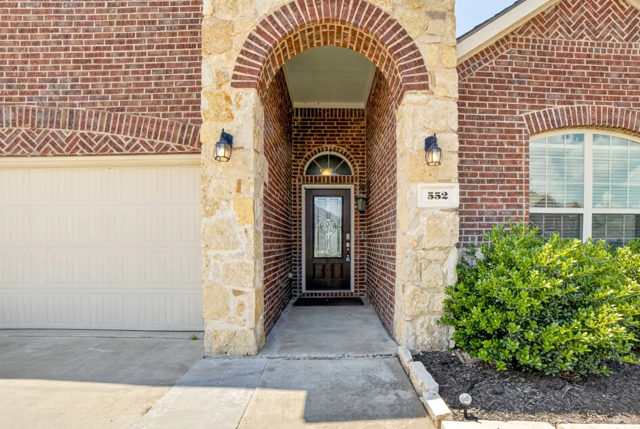 High arch leads to covered porch-entry.