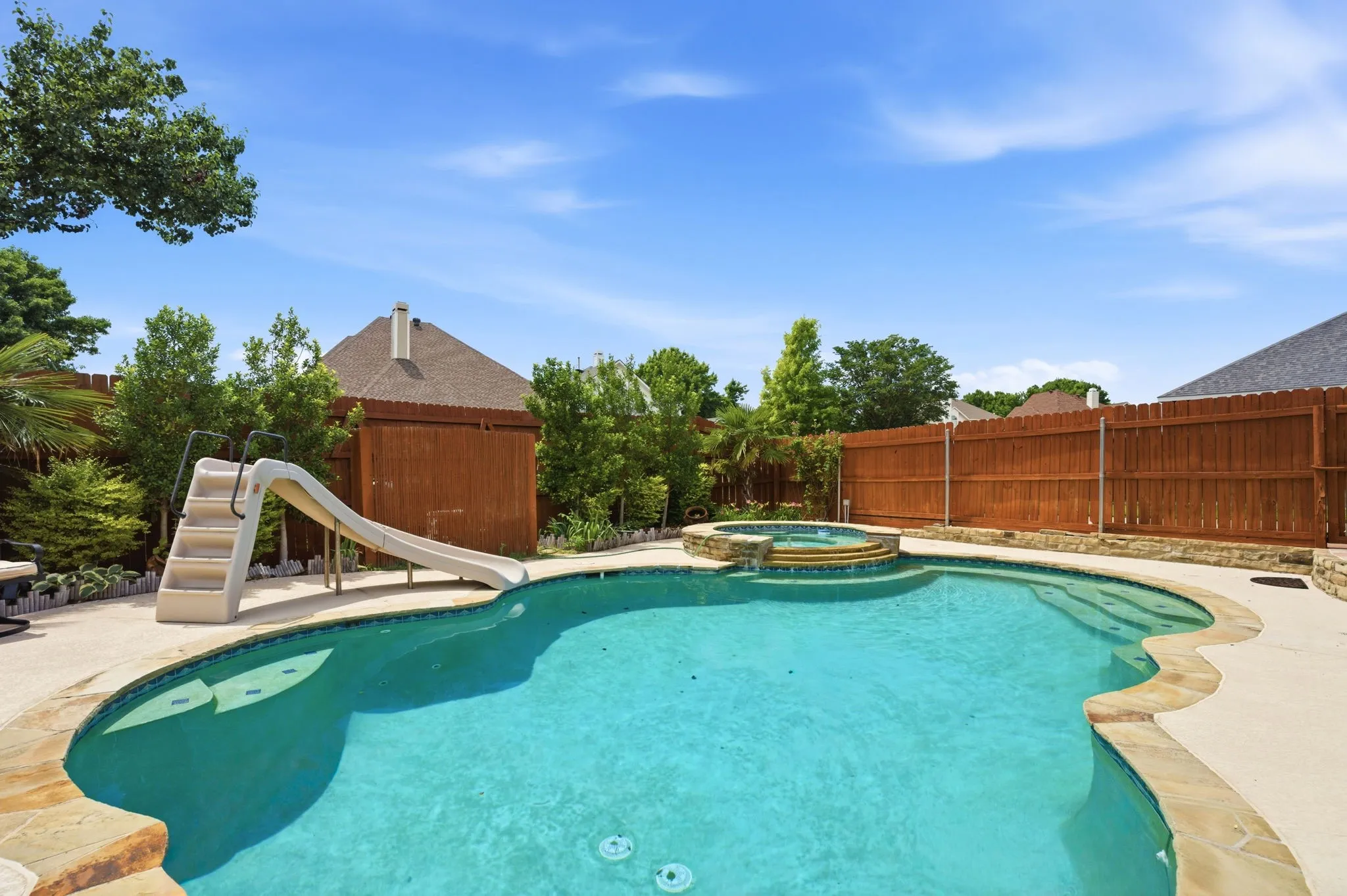 Freeform swimming pool with integrated spa and natural stone coping