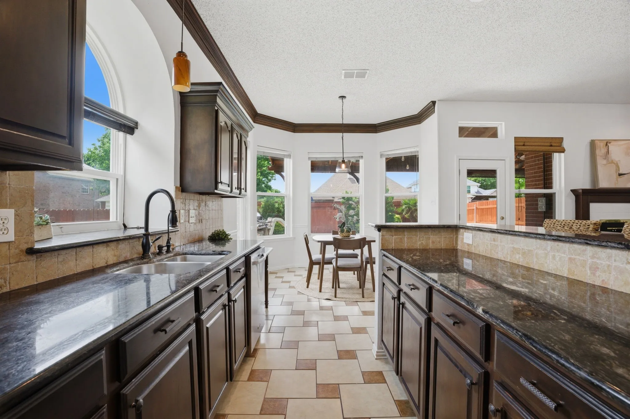 Kitchen featuring dark wood cabinetry, a tile backsplash, and dark polished countertops