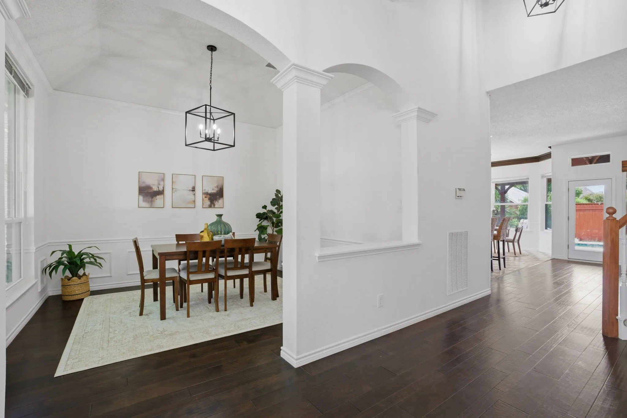 Dining area featuring dark wood-finish flooring, wainscoting, and an arched entryway