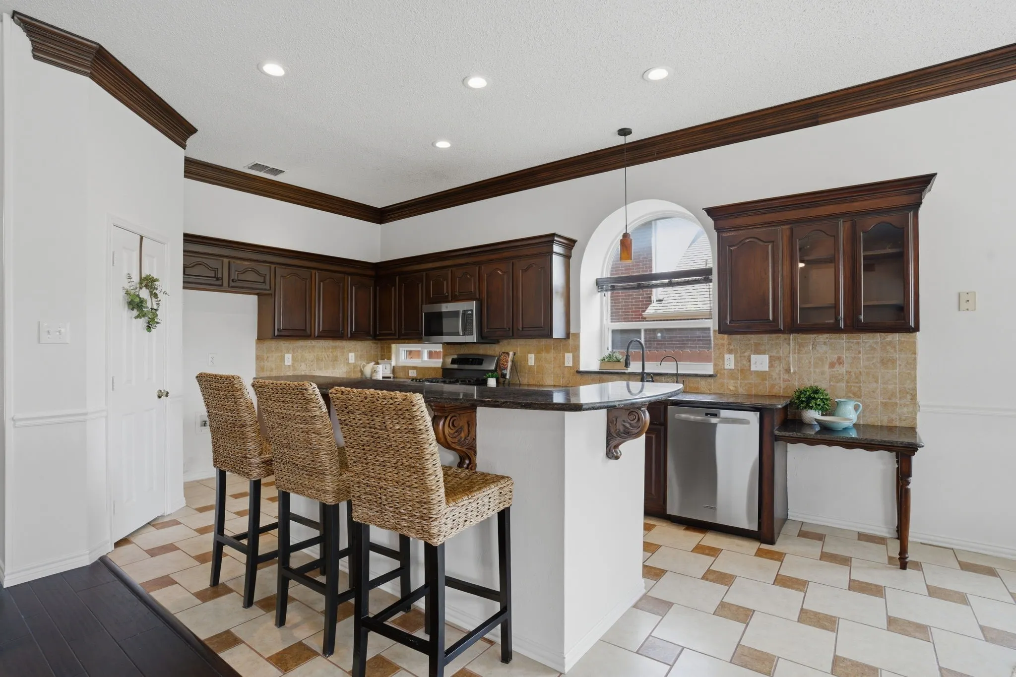 Kitchen featuring dark wood cabinetry, granite countertops, stainless steel appliances, and a tiled backsplash