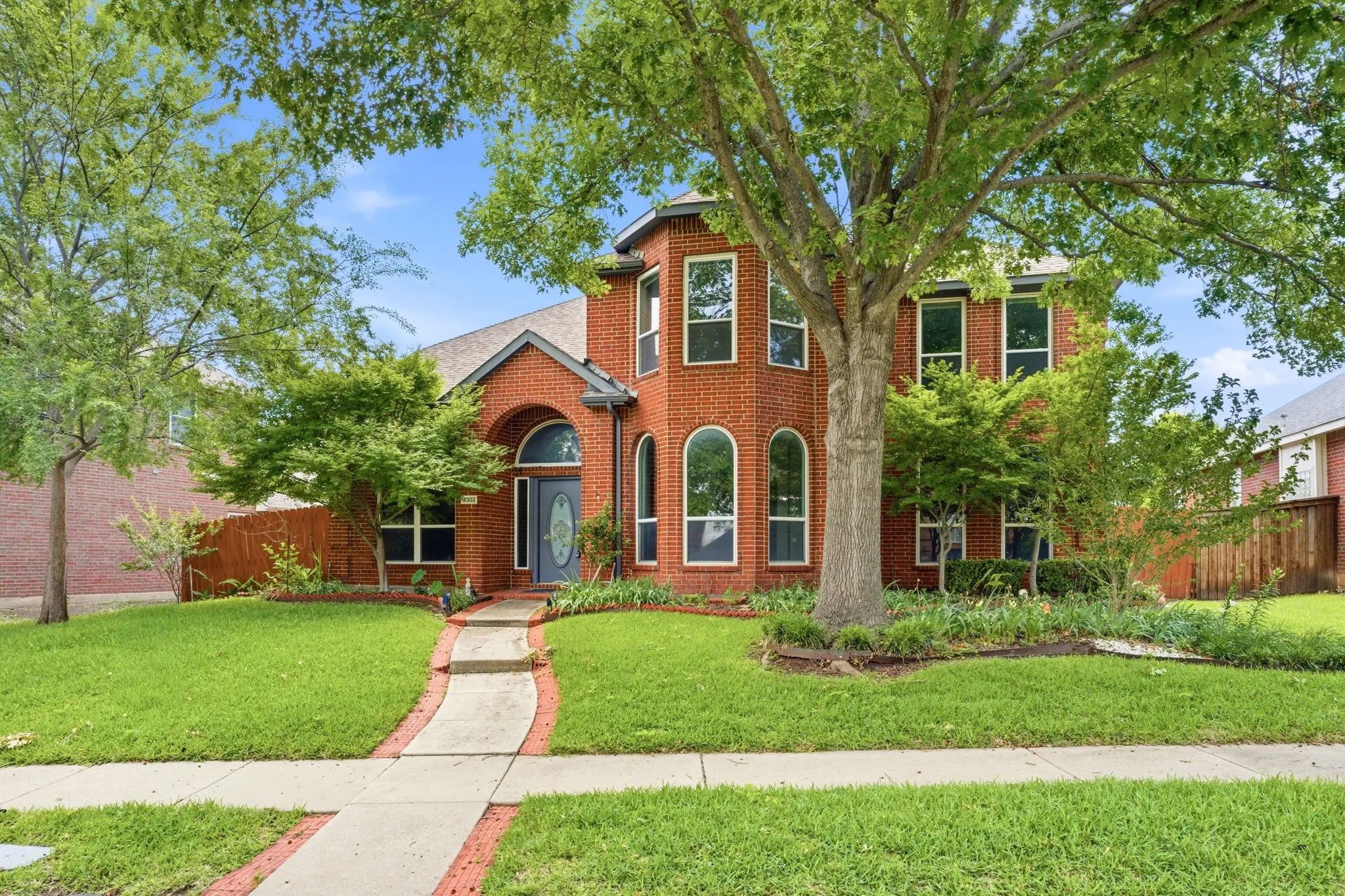 Traditional brick exterior with a prominent arched entry, featuring a decorative glass front door and multiple arched windows
