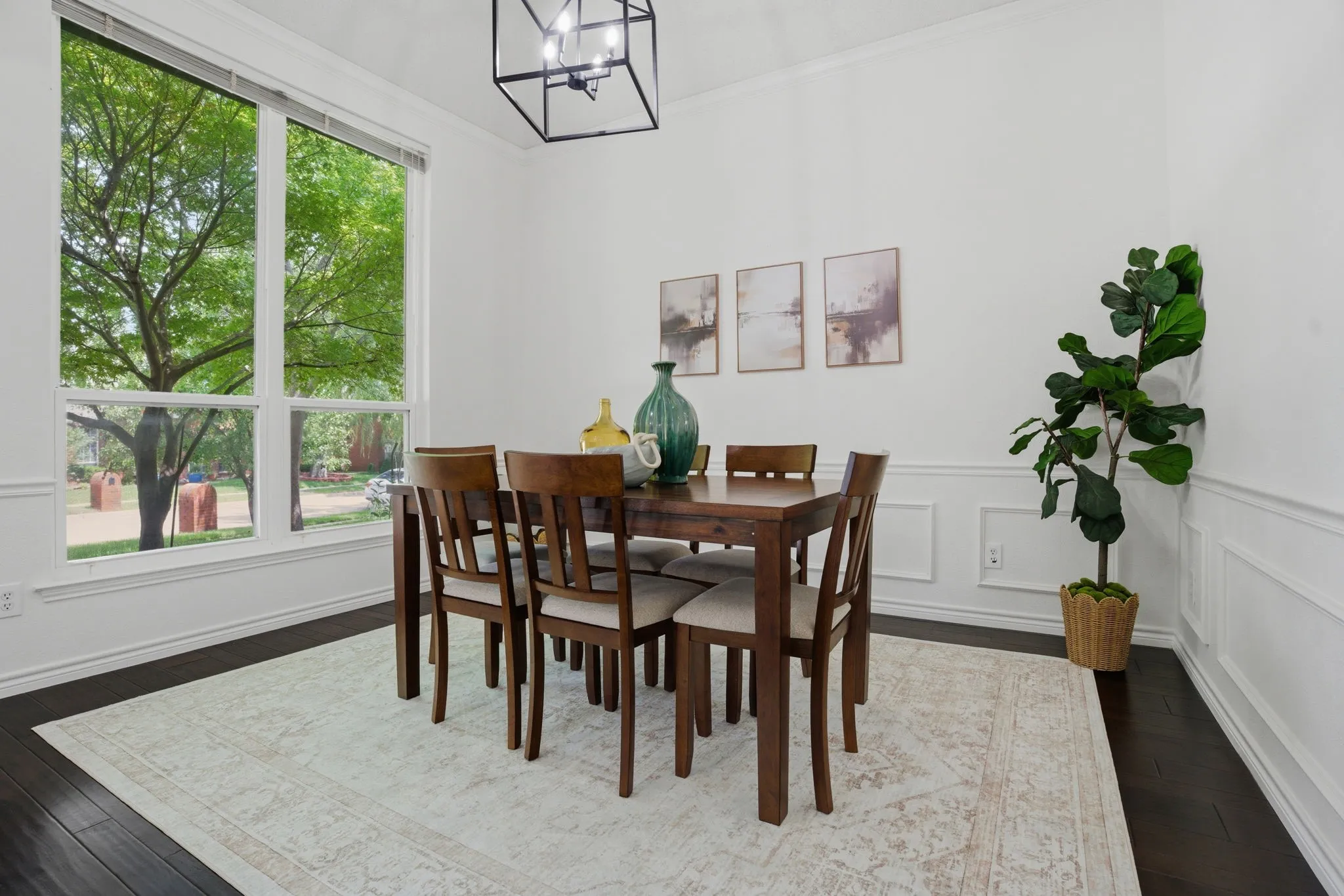 Dining area featuring a large window, dark wood-finish flooring, white wainscoting, and a linear chandelier
