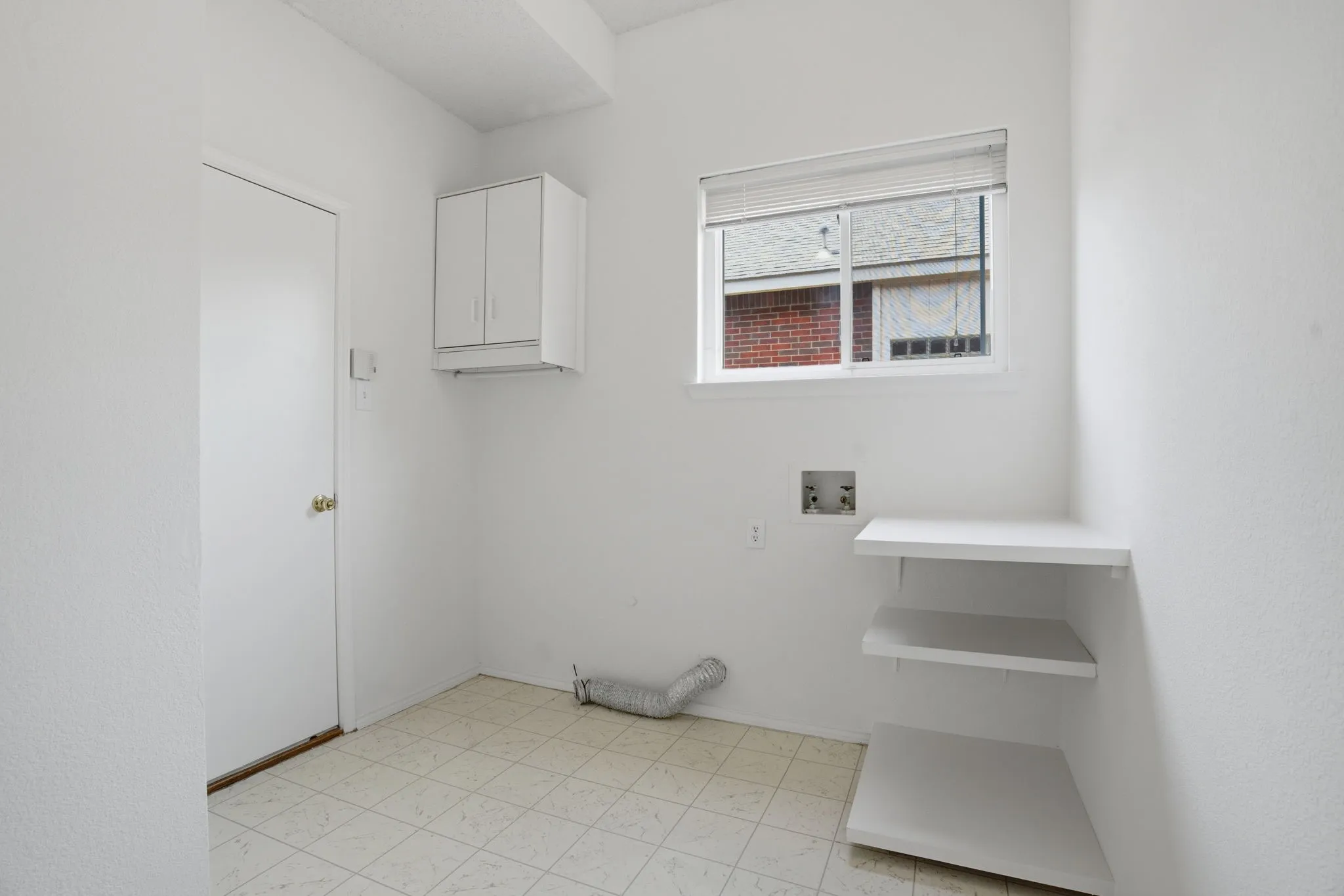 Dedicated laundry space featuring white cabinetry, built-in shelving, and light-toned patterned flooring