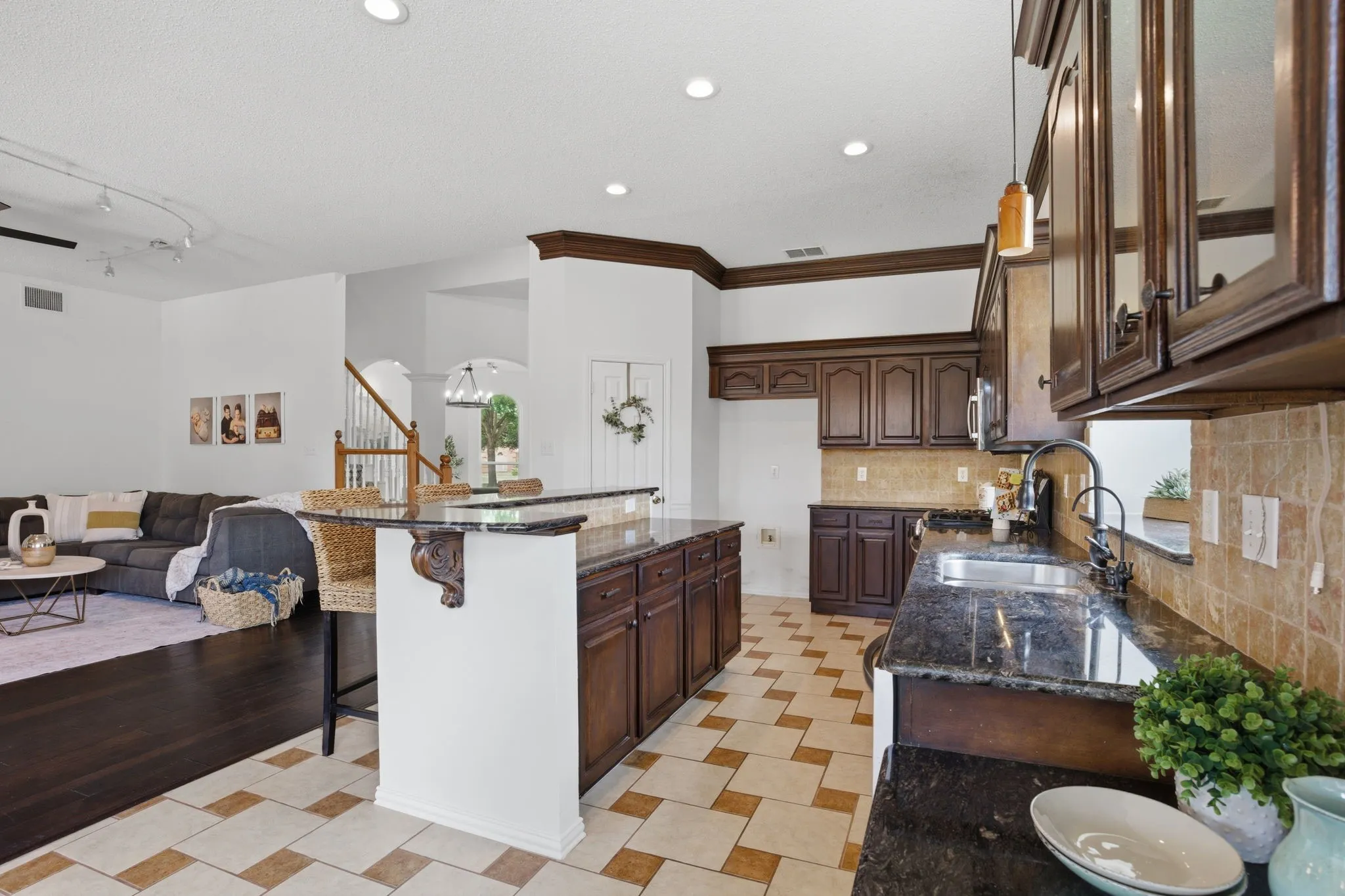 Open-concept kitchen and living area featuring dark wood-finish cabinetry, granite countertops, and a tile backsplash