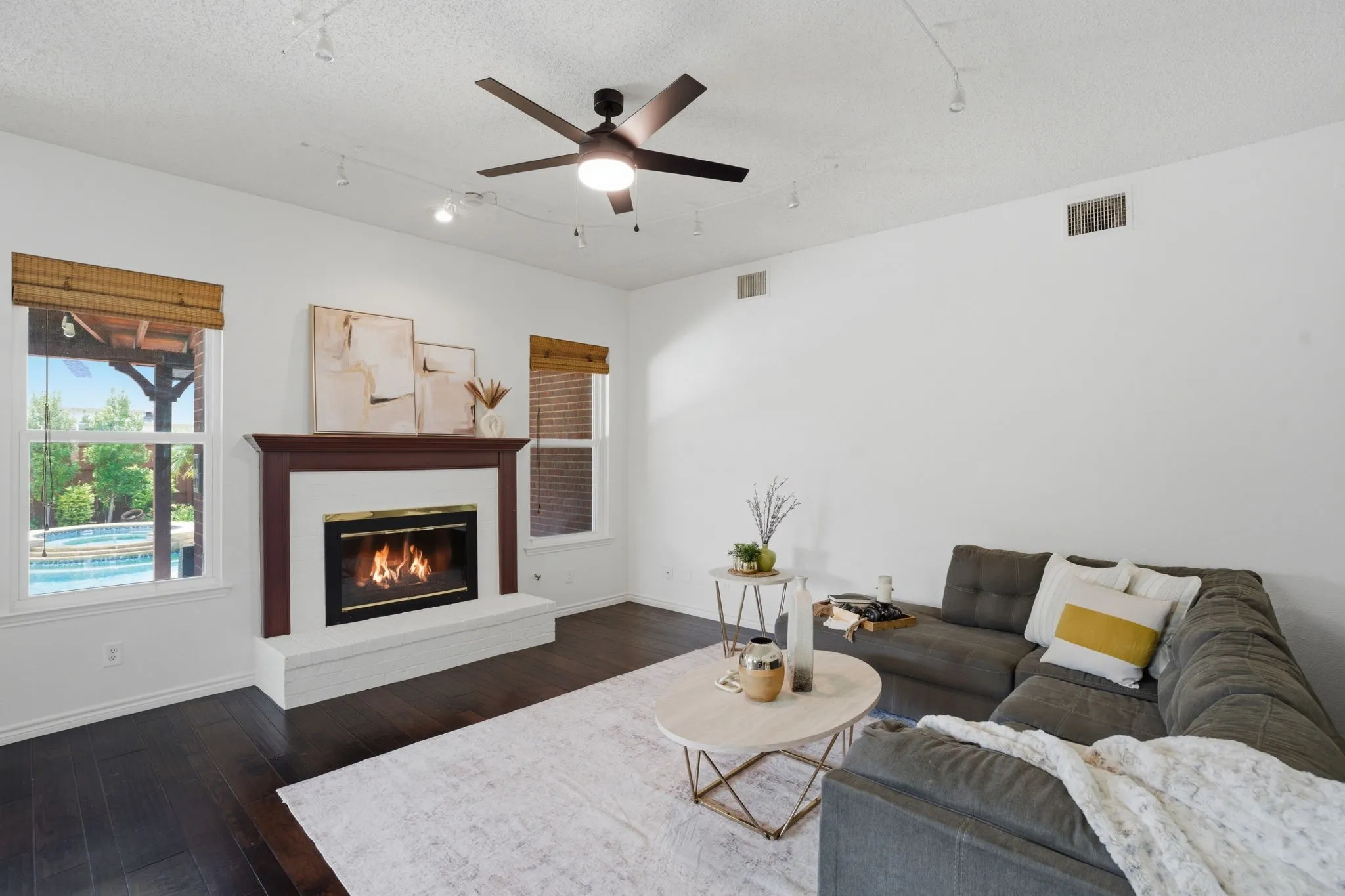 Living area featuring dark wood-finish flooring, a contemporary ceiling fan, and track lighting