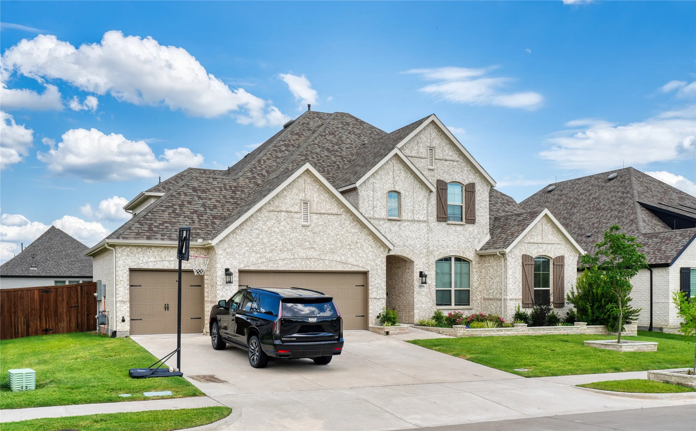 French country style house with concrete driveway, brick siding, a shingled roof, and an attached garage