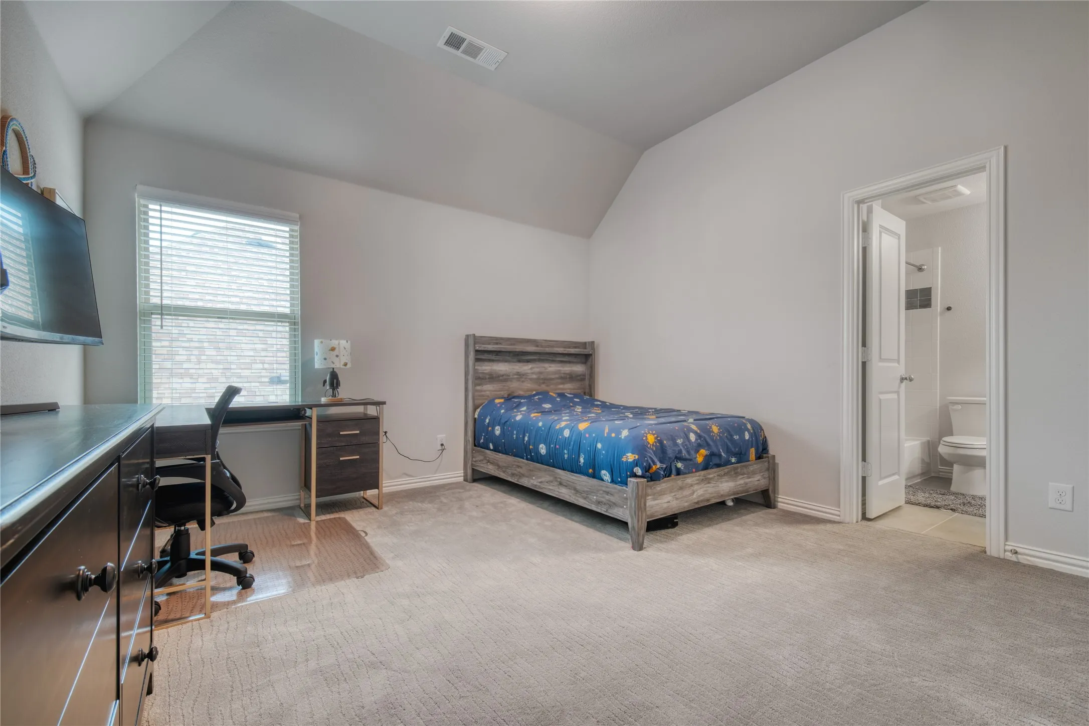 Bedroom with vaulted ceiling, carpet, an office area, and ensuite bath