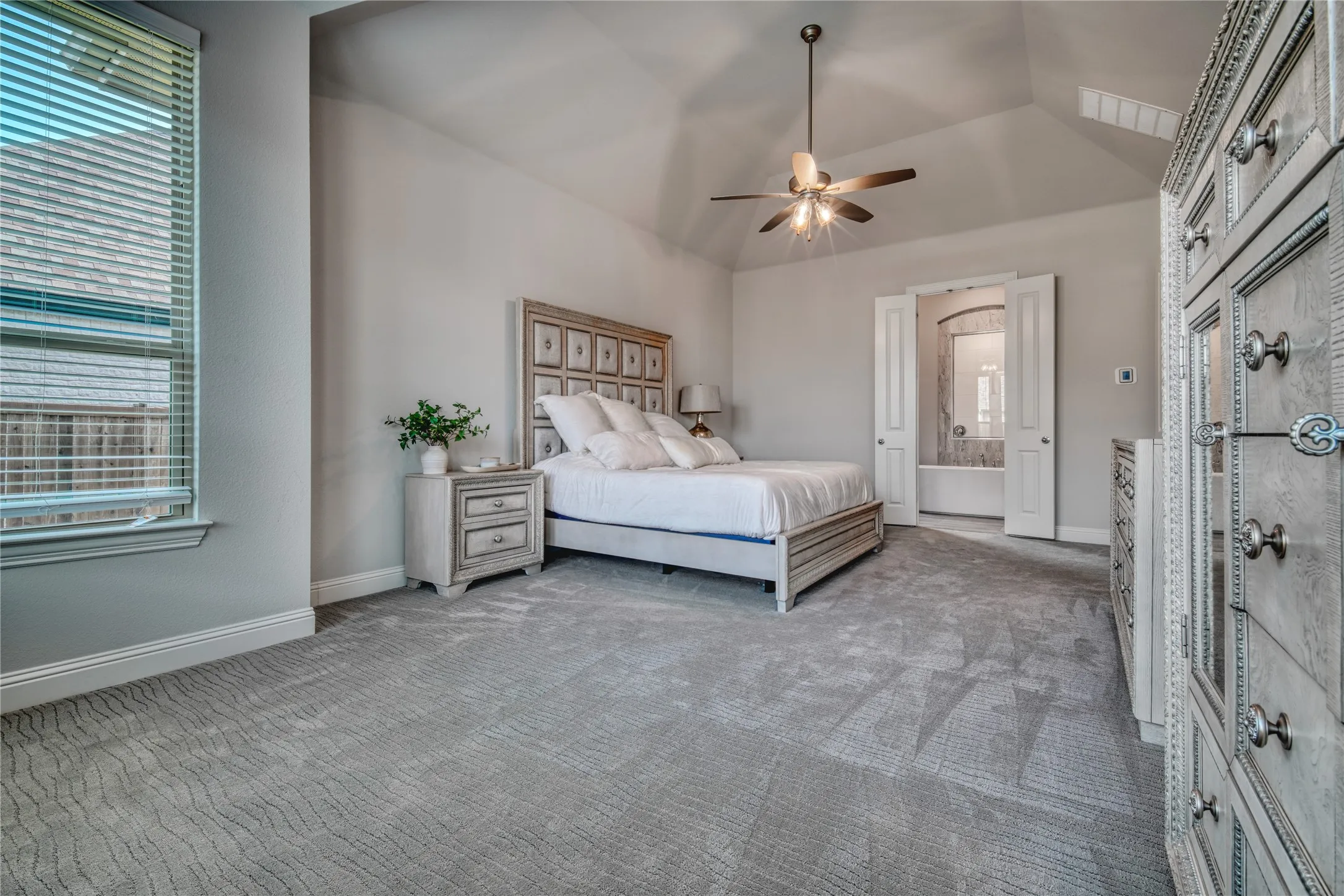 Carpeted bedroom with lofted ceiling, ensuite bathroom, and ceiling fan