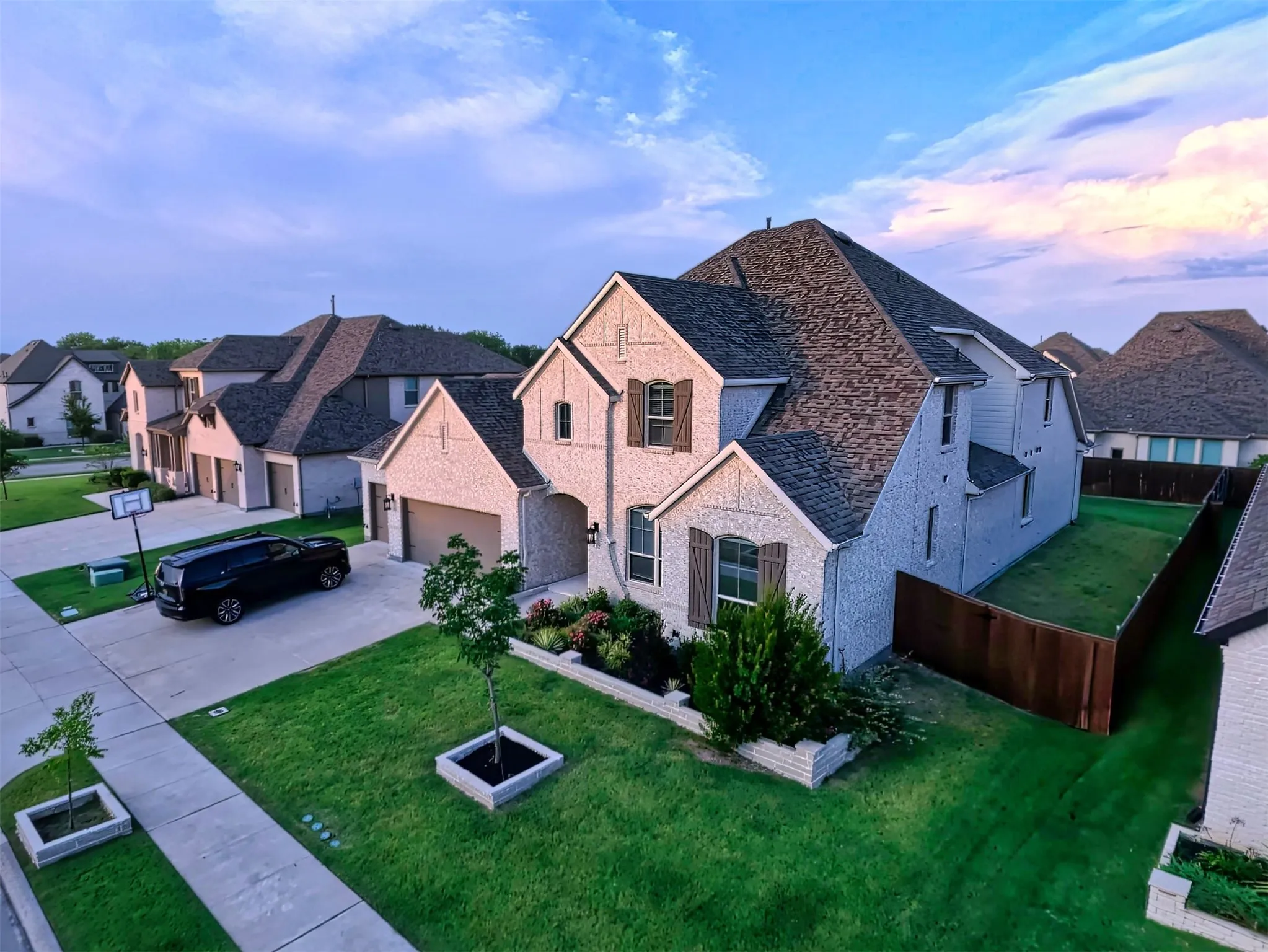 French country style house with driveway, a residential view, an attached garage, brick siding, and a shingled roof