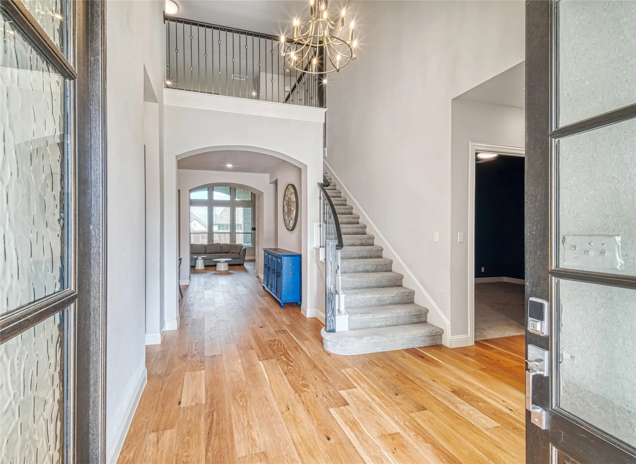 Entryway with wood finished floors, arched walkways, stairs, a towering ceiling, and a chandelier