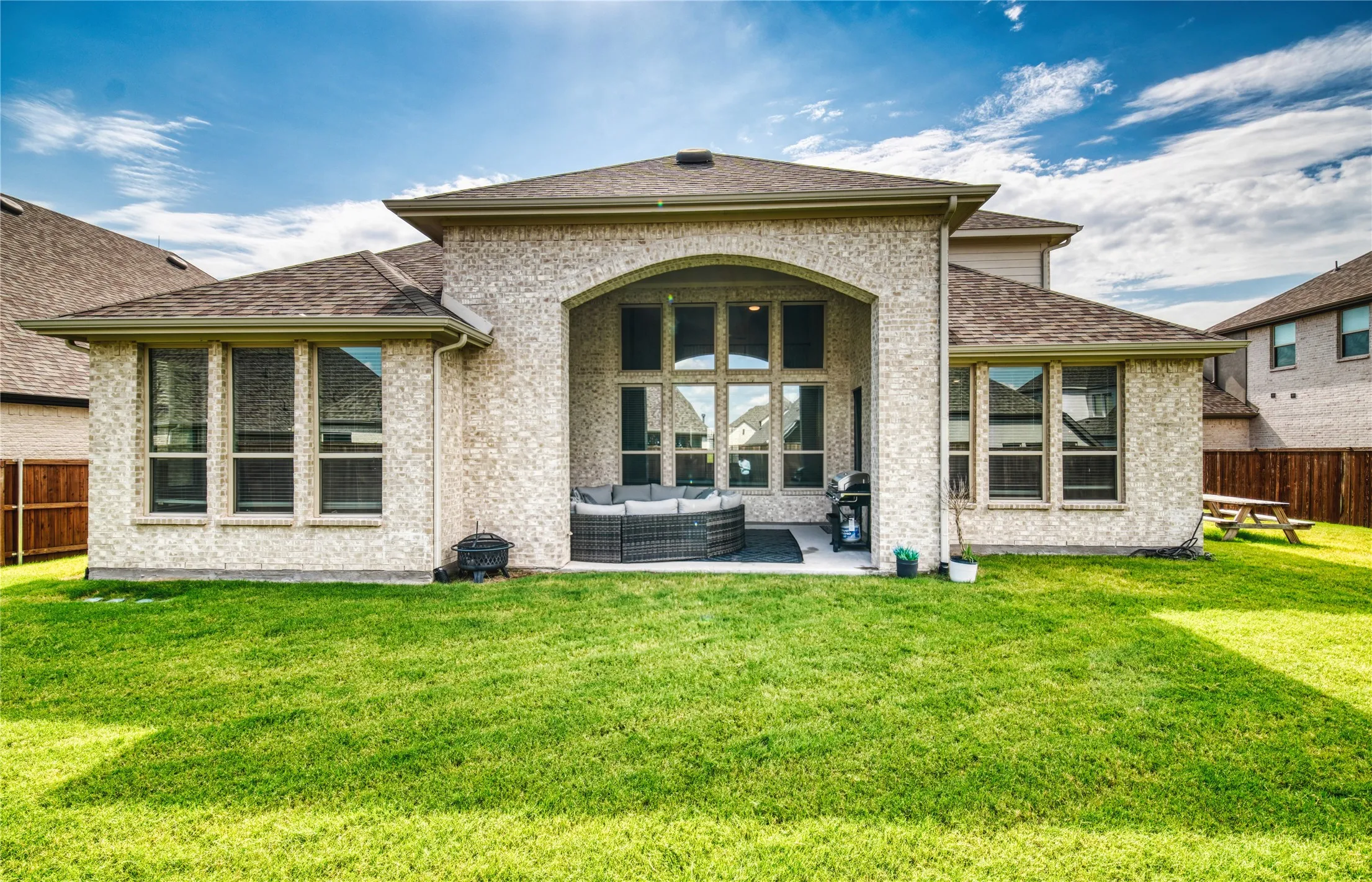 Back of property with an outdoor hangout area, a patio, roof with shingles, and brick siding