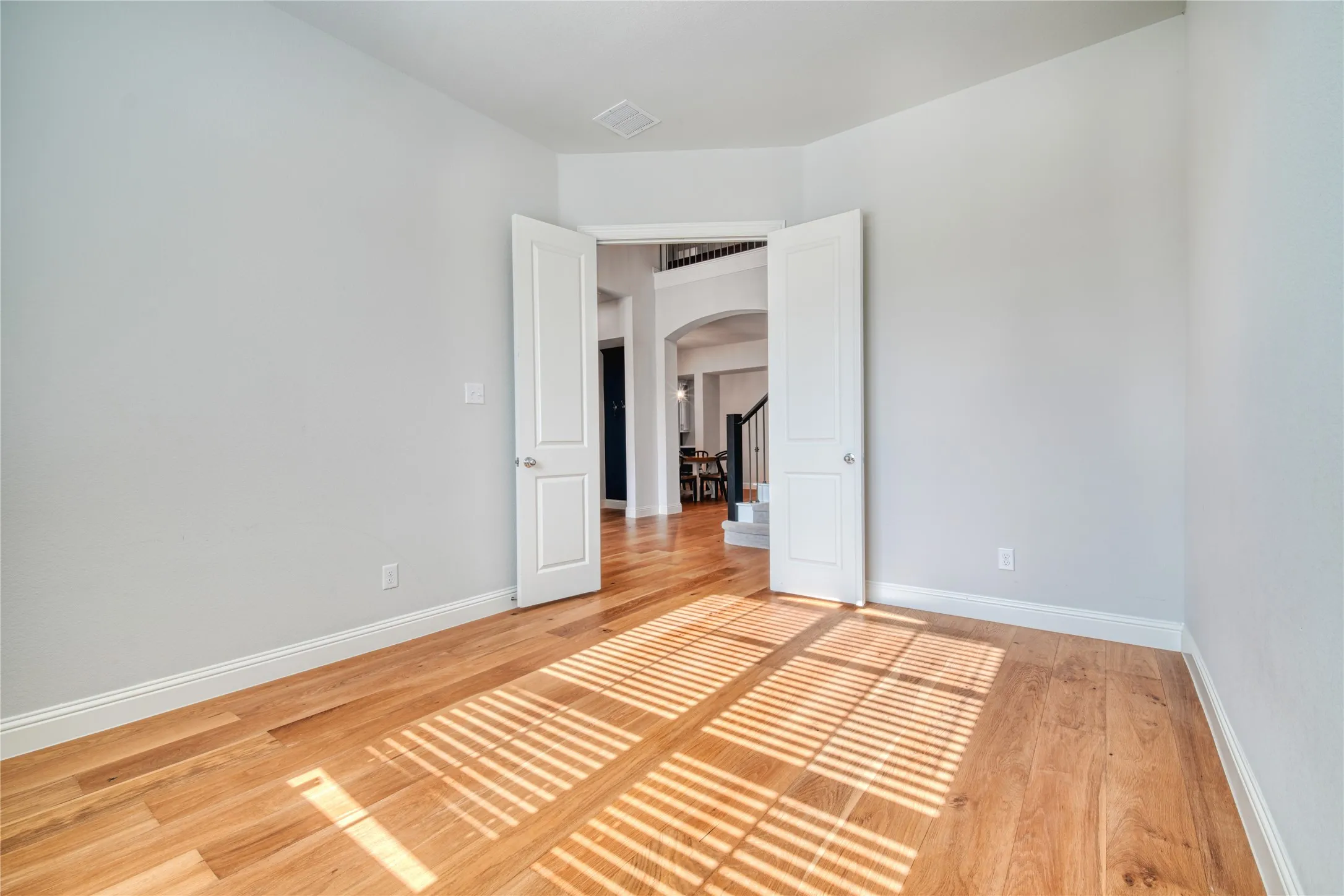 Spare room with arched walkways and light wood-style flooring