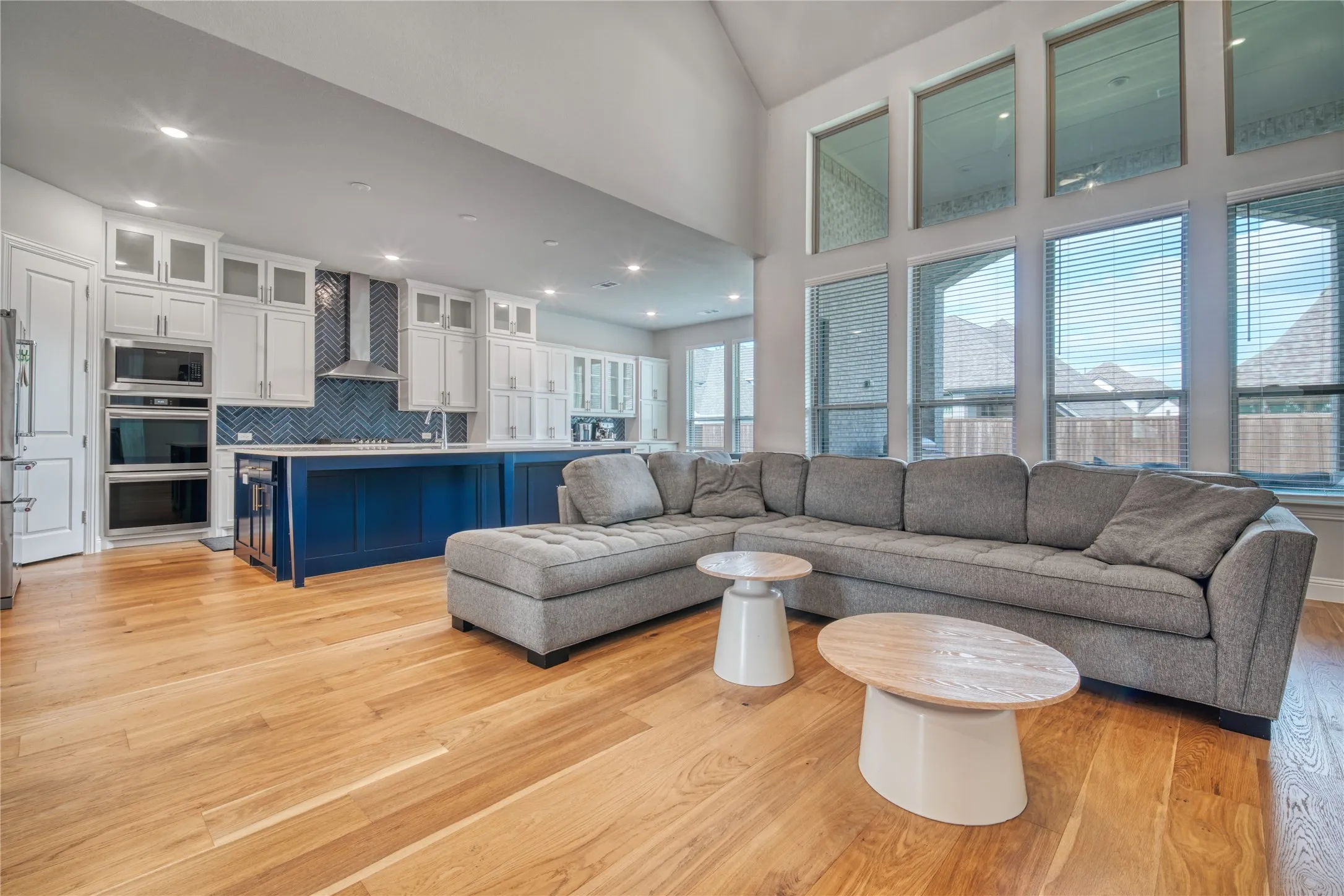 Living area with light wood-style floors, high vaulted ceiling, and recessed lighting