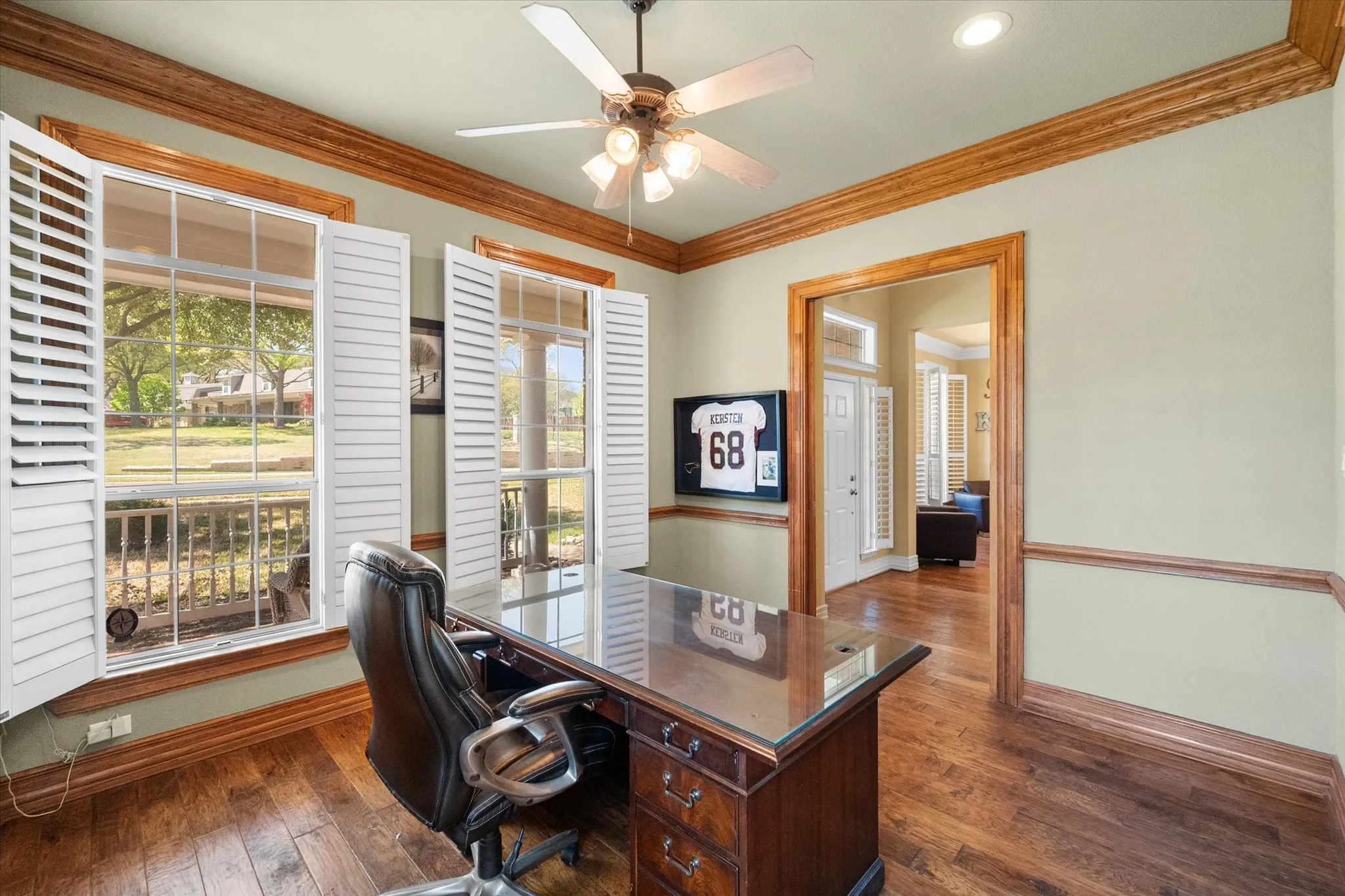 Elegant **home office with glass French doors** offers a private yet connected workspace filled with natural light. Featuring **rich wood flooring, crown molding, and custom built-in bookshelves**, this space blends functionality with timeless design. The **double French door entry** creates a sophisticated focal point while allowing for seamless flow and visibility. Ideal for a **home office, study, or flex space**, this room delivers both style and productivity with classic architectural details and warm wood finishes.