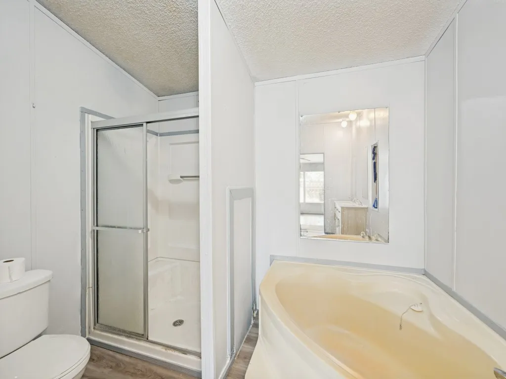 Bathroom featuring a corner soaking tub, a stand-up shower with sliding glass doors, and a wall-mounted​​‌​​​​‌​​‌‌​‌‌​​​‌‌​‌​‌​‌​​​‌​​ mirror