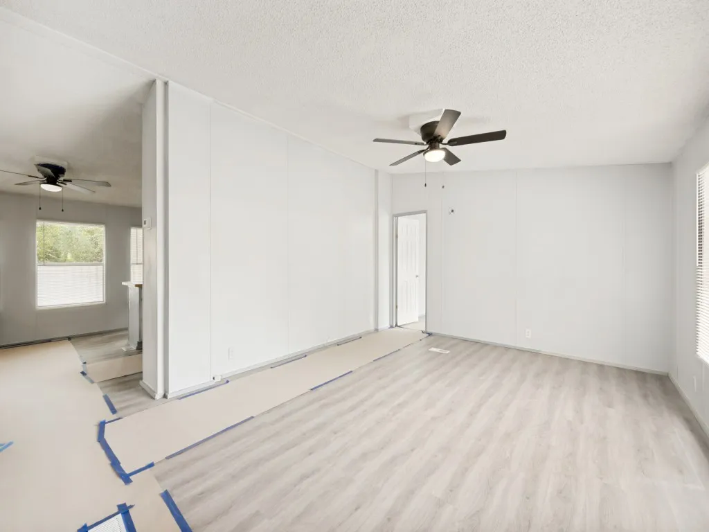 Open concept living area featuring light wood-finish flooring, a contemporary ceiling fan, and white vertical paneling