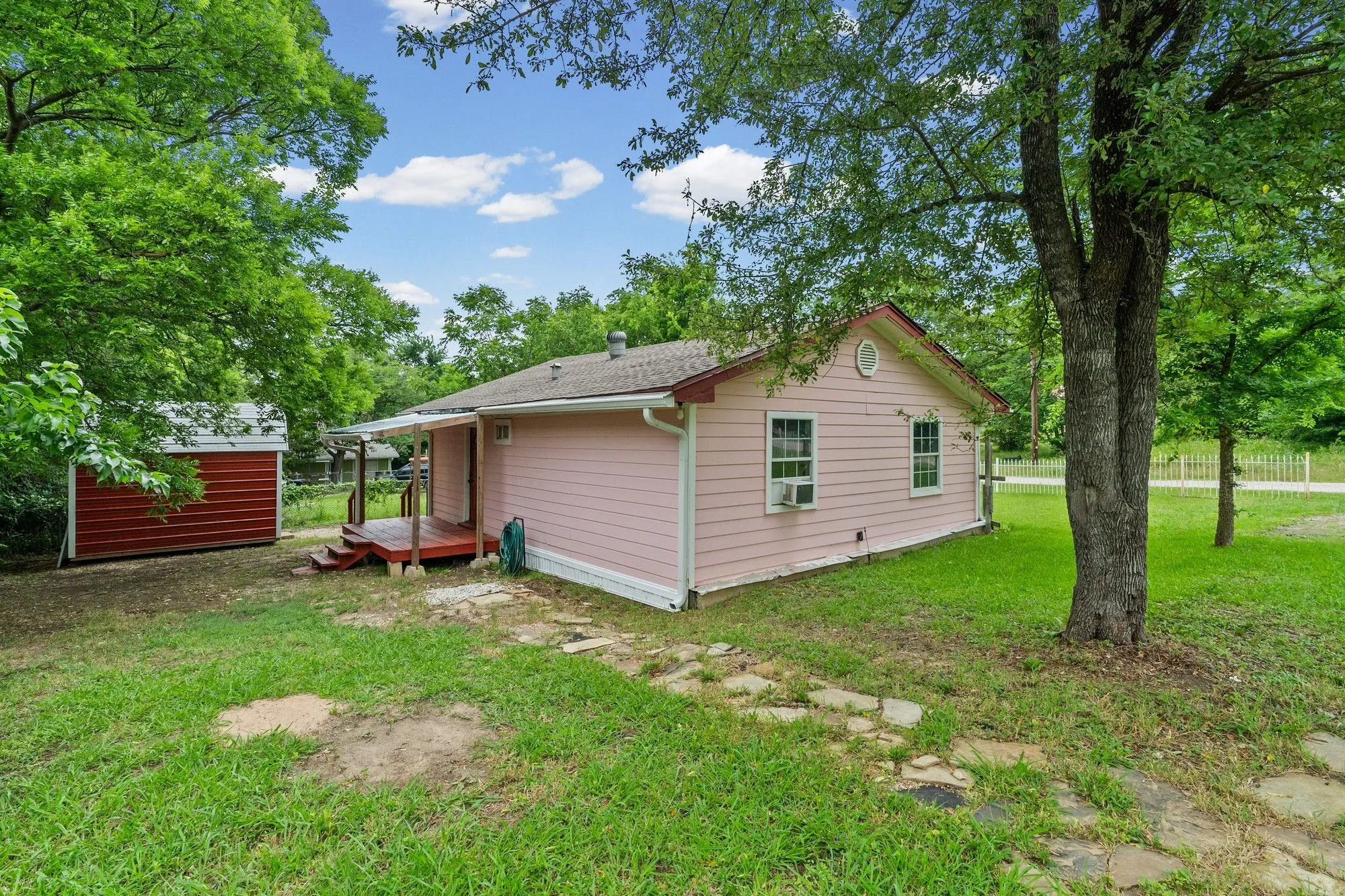 Pink siding exterior with white trim, a gabled roof, and two front-facing windows