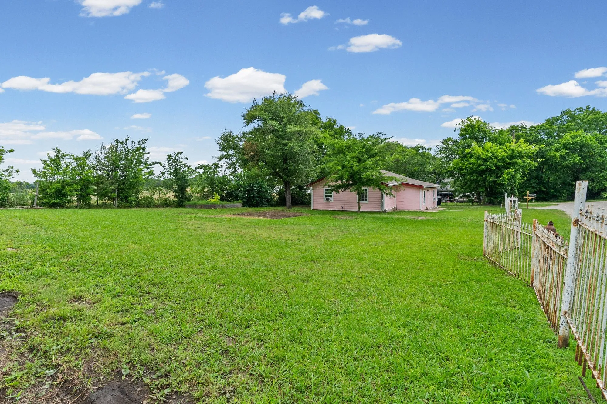 Expansive green lawn with mature trees and a distant pink exterior structure