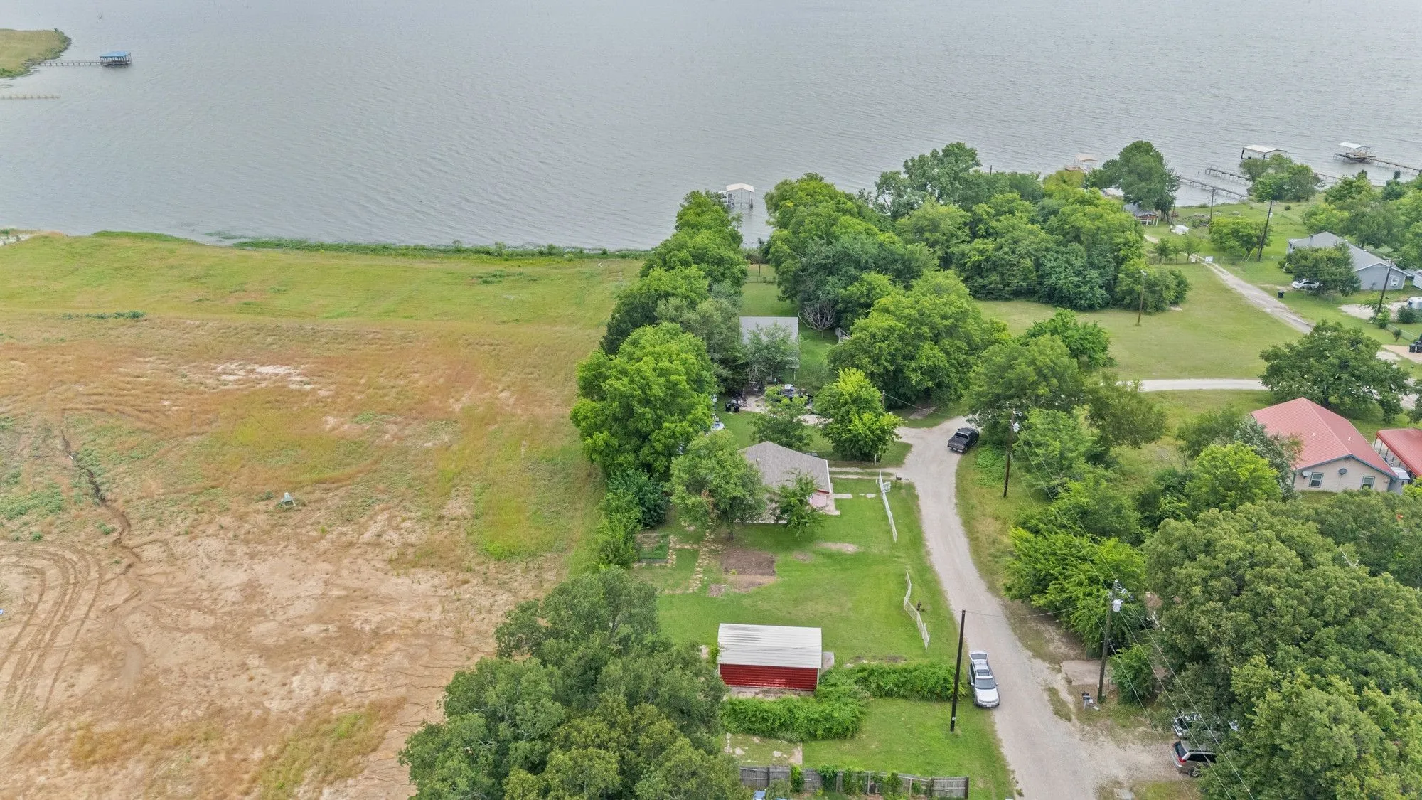 Expansive waterside property featuring a large parcel of undeveloped land, direct water frontage, and multiple mature trees
