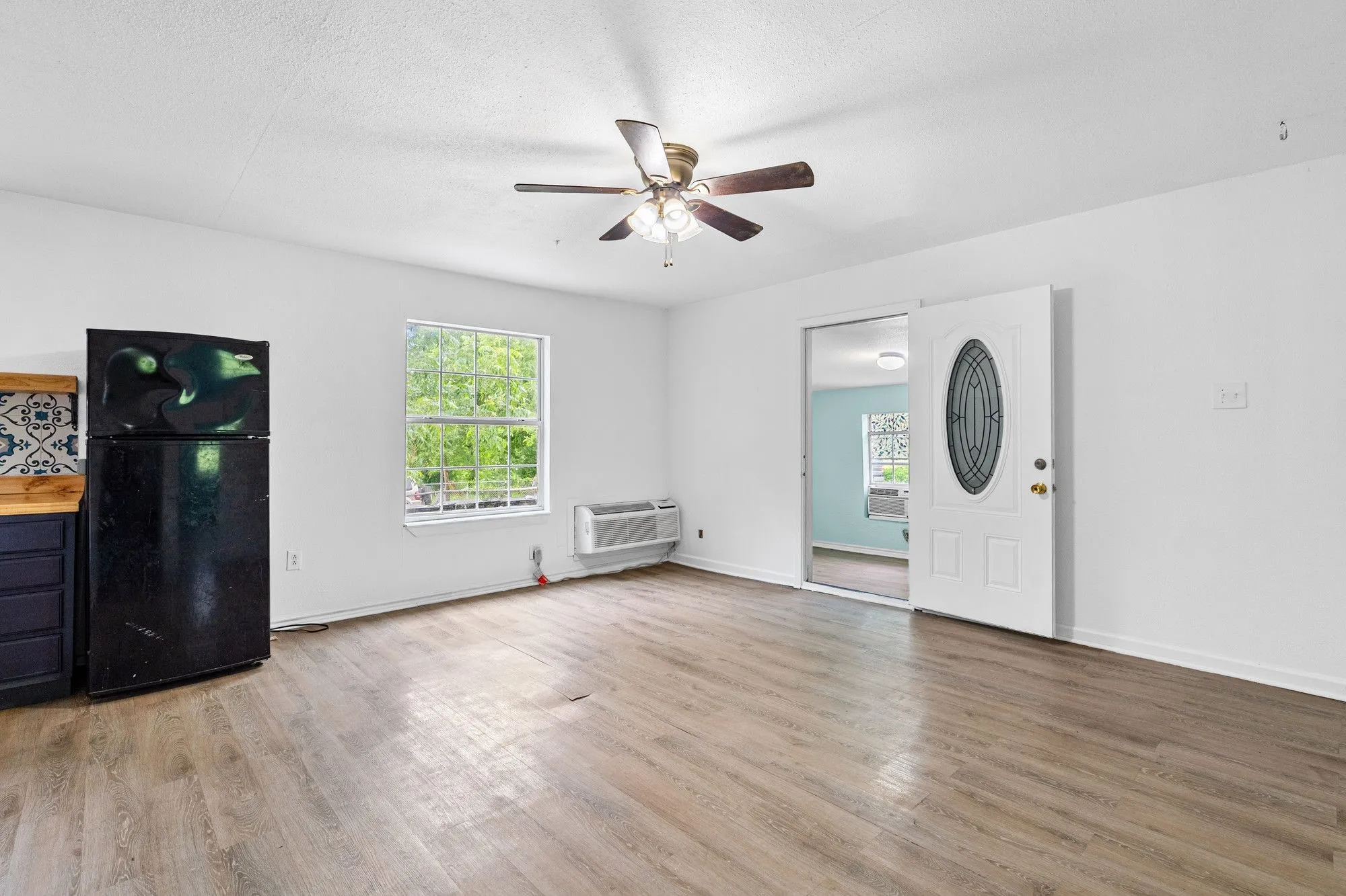 Main living area featuring wood-finish flooring, a ceiling fan, and white walls