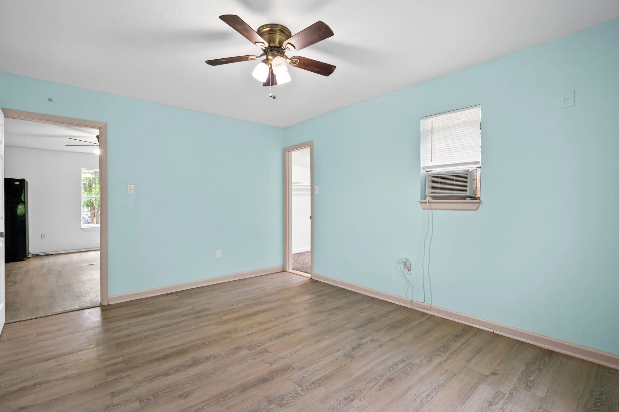 Interior room featuring wood-finish flooring, light blue walls, and white ceiling