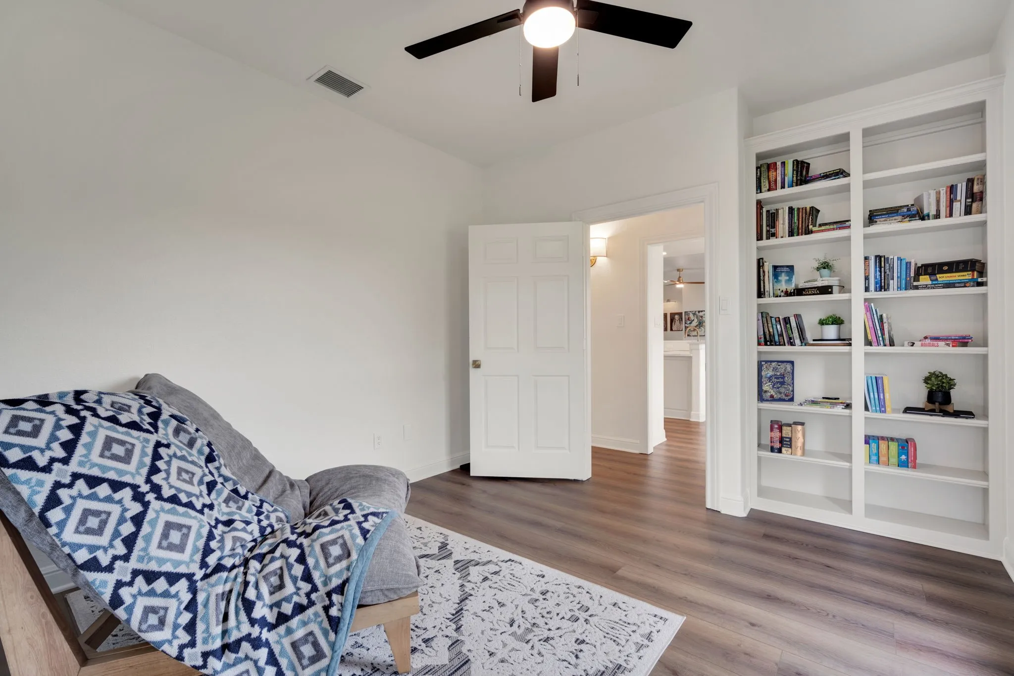 Office or sitting with built-in shelving, a ceiling fan with integrated lighting, and white trim.