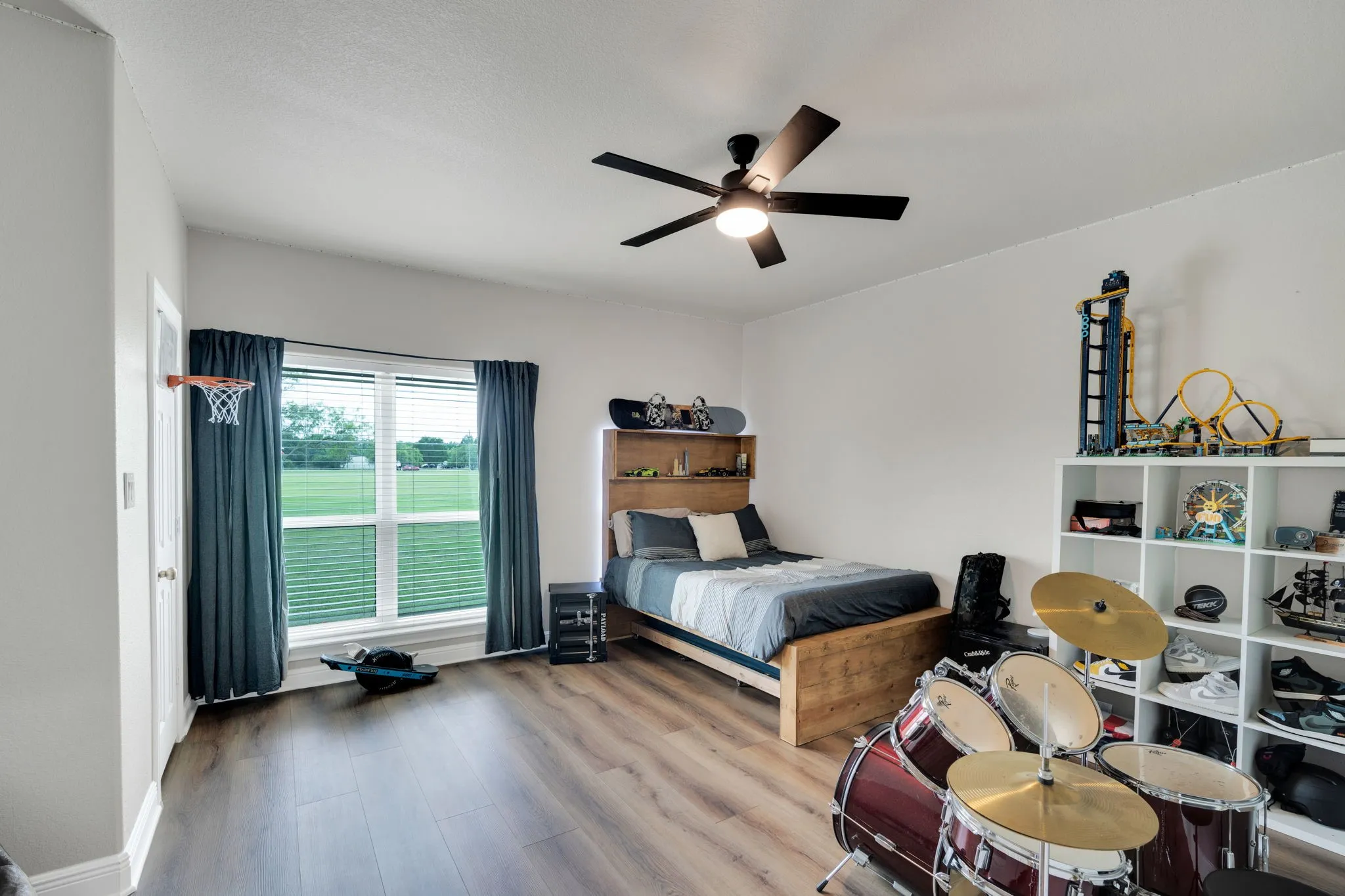 Bedroom 2 featuring a large window with a view of the front yard, a ceiling fan with integrated lighting, and a walk-in closet.