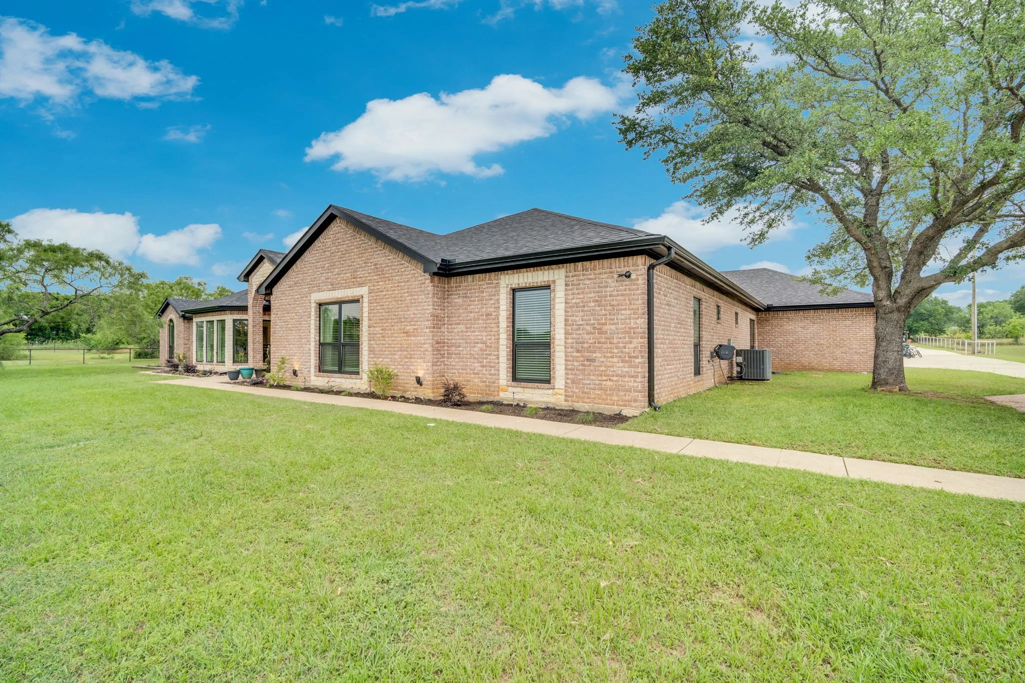 Brick exterior with dark framed windows and a dark shingle roof