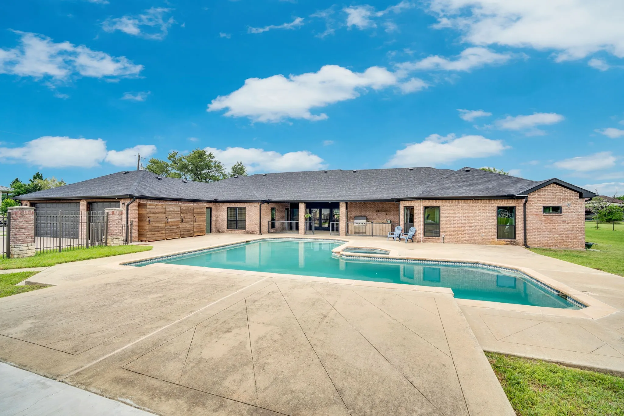 Expansive concrete pool deck surrounding an inground swimming pool with an integrated spa