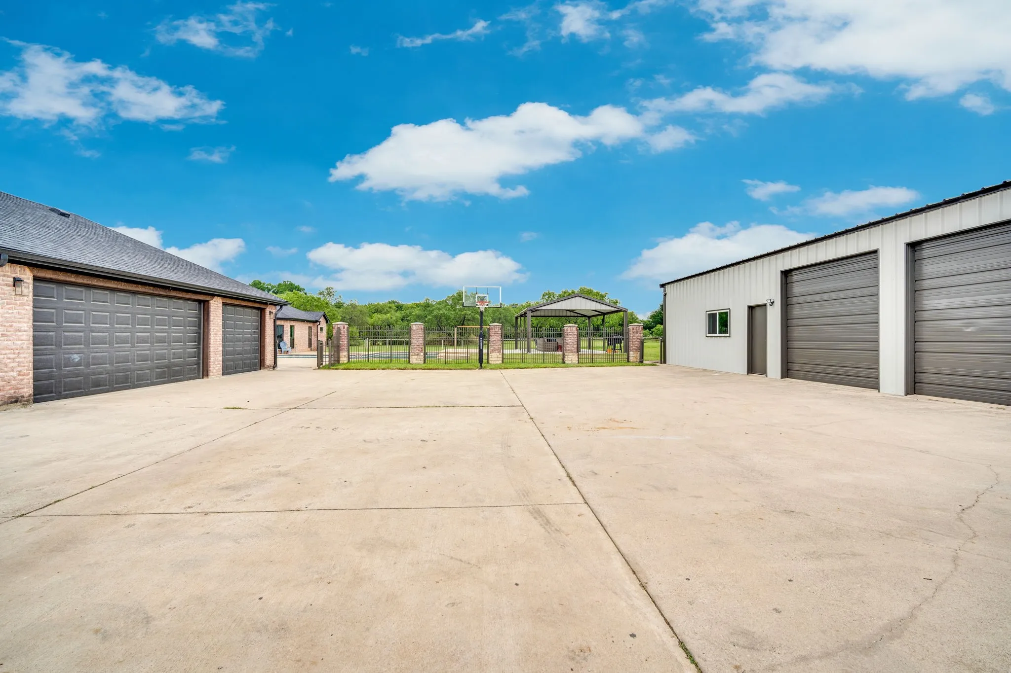 Expansive concrete driveway that connects the three car garage ont he main house to the shop (featuring an office and a gym) with a basketball court area.