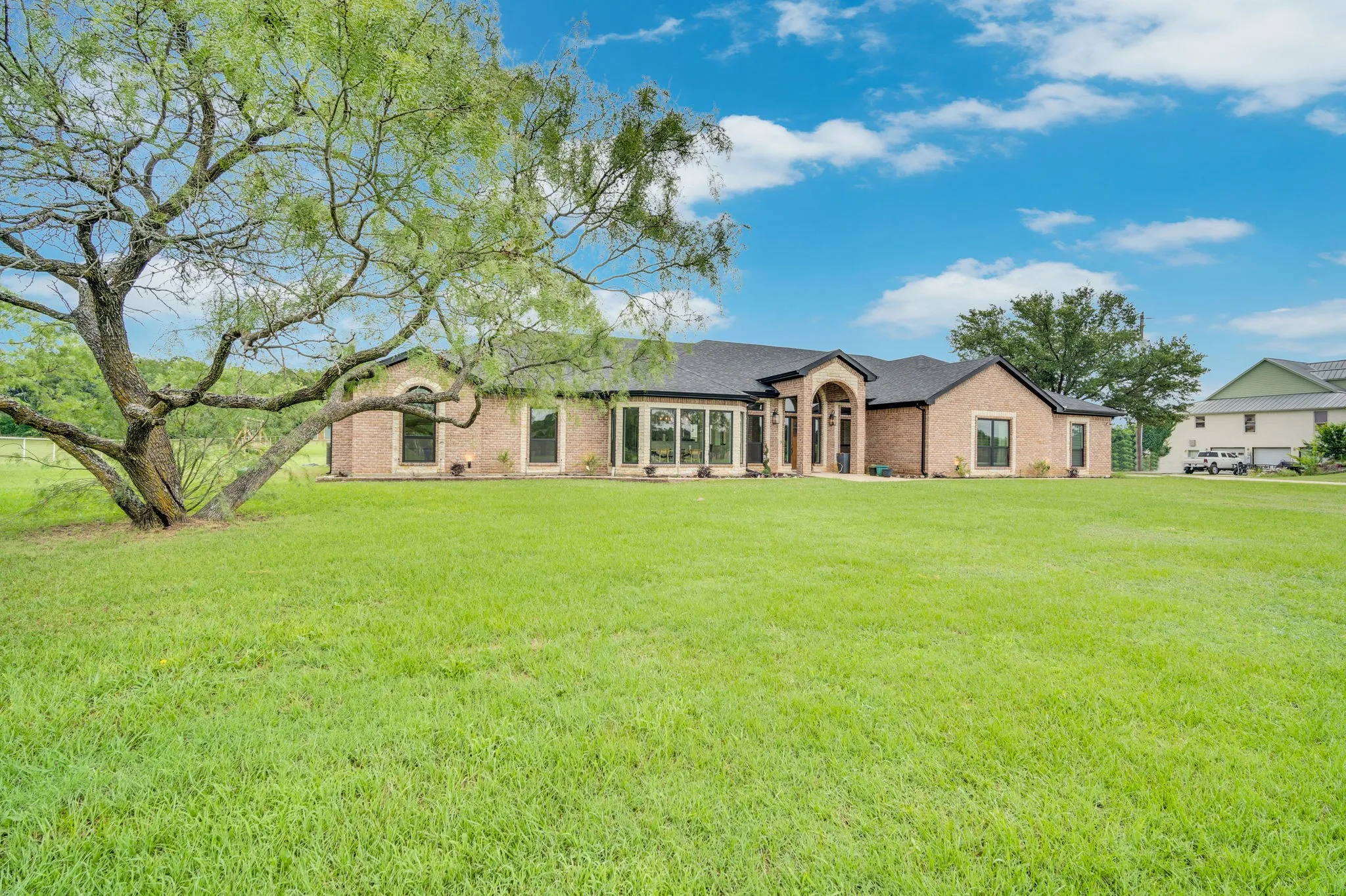 Expansive green lawn with a mature tree, complementing the brick exterior residence