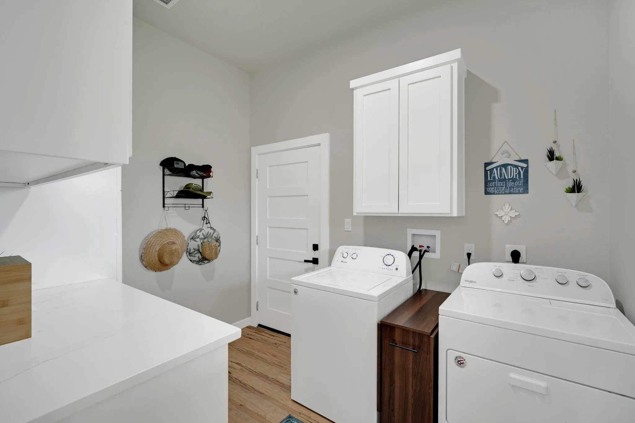 Dedicated laundry area featuring a white shaker-style wall cabinet, a white countertop, and a solid white door with black hardware
