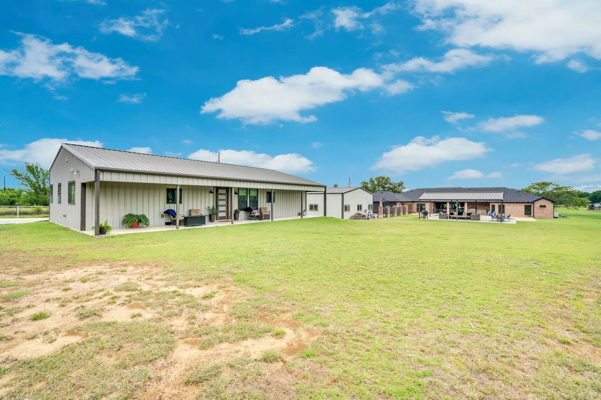 Expansive green space featuring the front of the second home and the patio with metal roofing