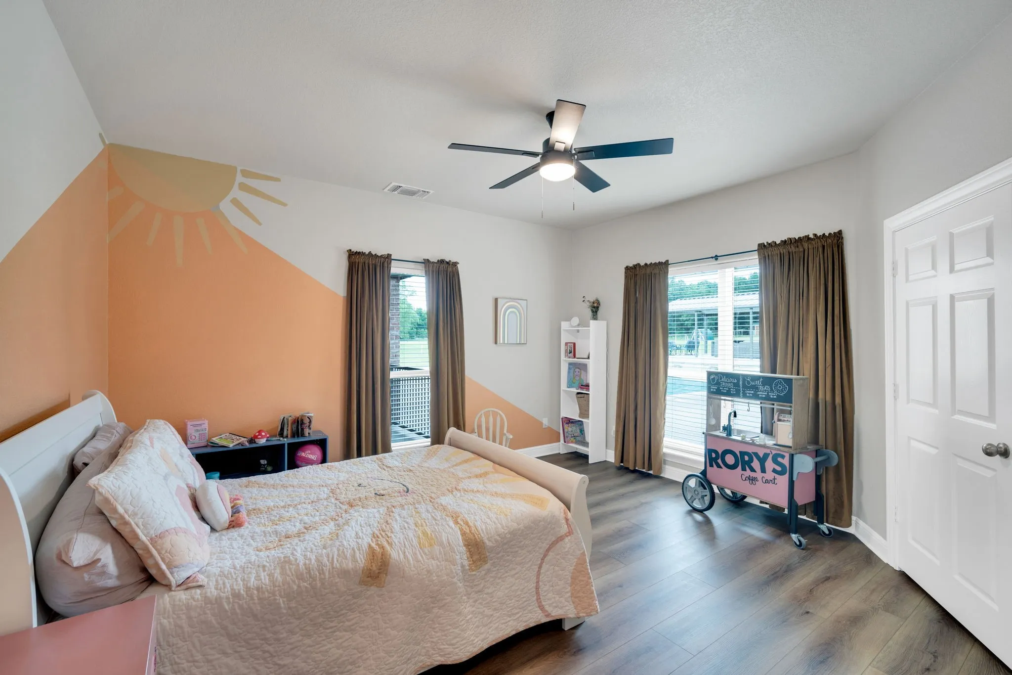 Bedroom 4 featuring two large windows with a view of the pool and patio, a ceiling fan with light fixture, sitting nook with upper cabinetry, and a walk-in closet.