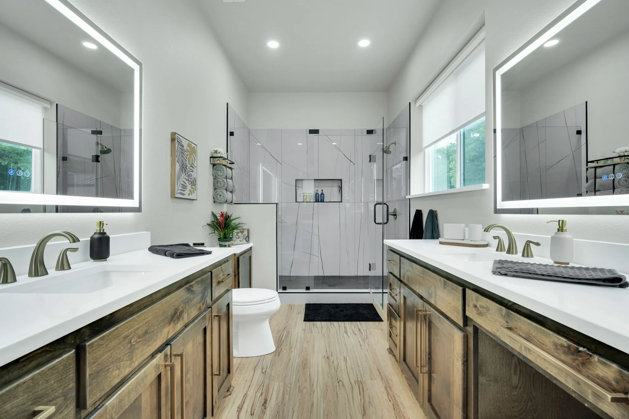 Dual vanities featuring undermount sinks and modern illuminated mirrors