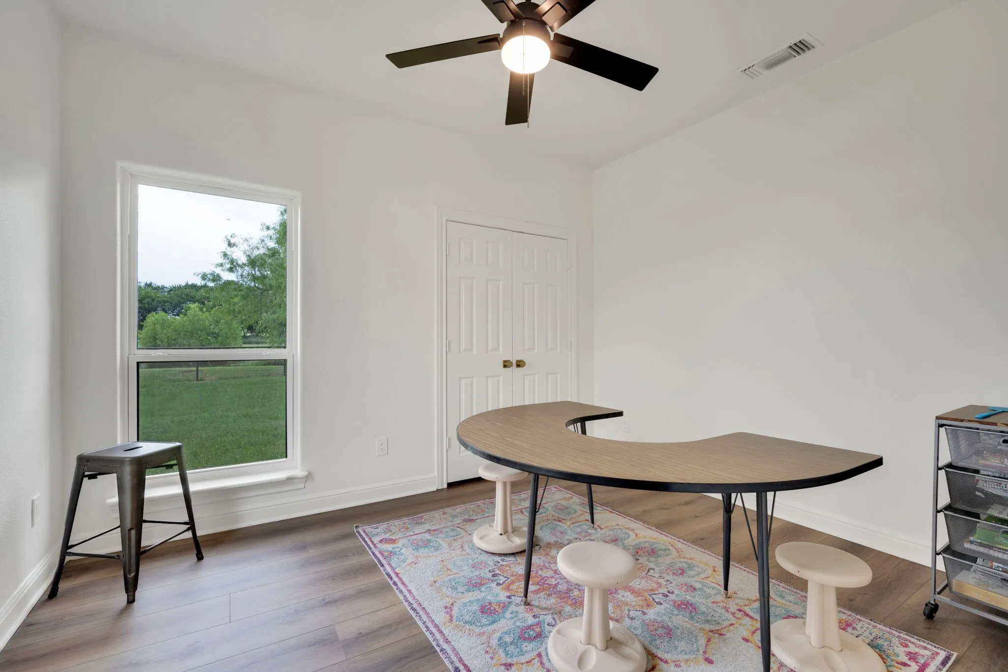 Bright room (6th bedroom) featuring a large white-framed window, french door closet, and a ceiling fan.