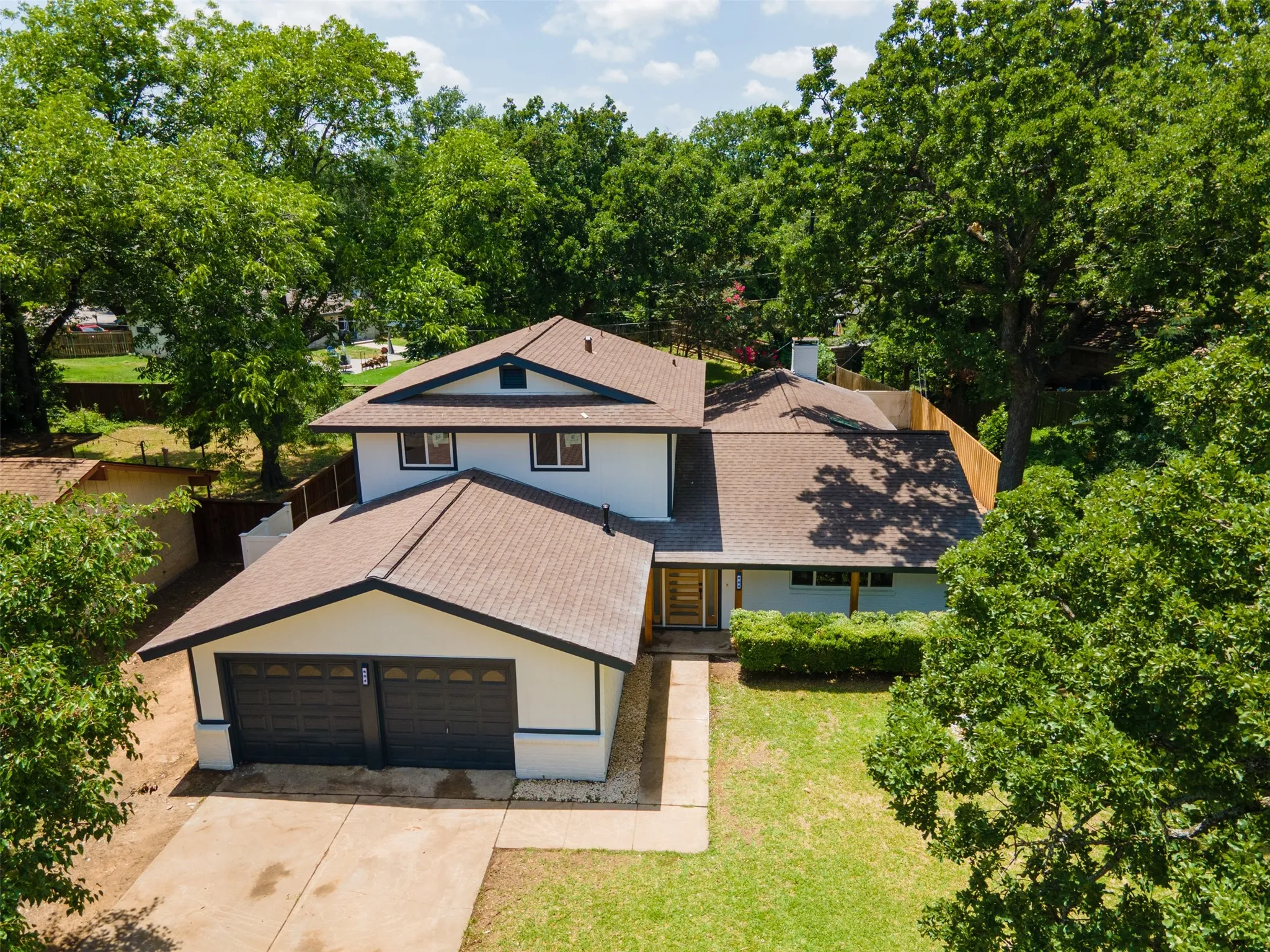 Contemporary two-story residence featuring a two-car garage, concrete driveway, and mature landscaping