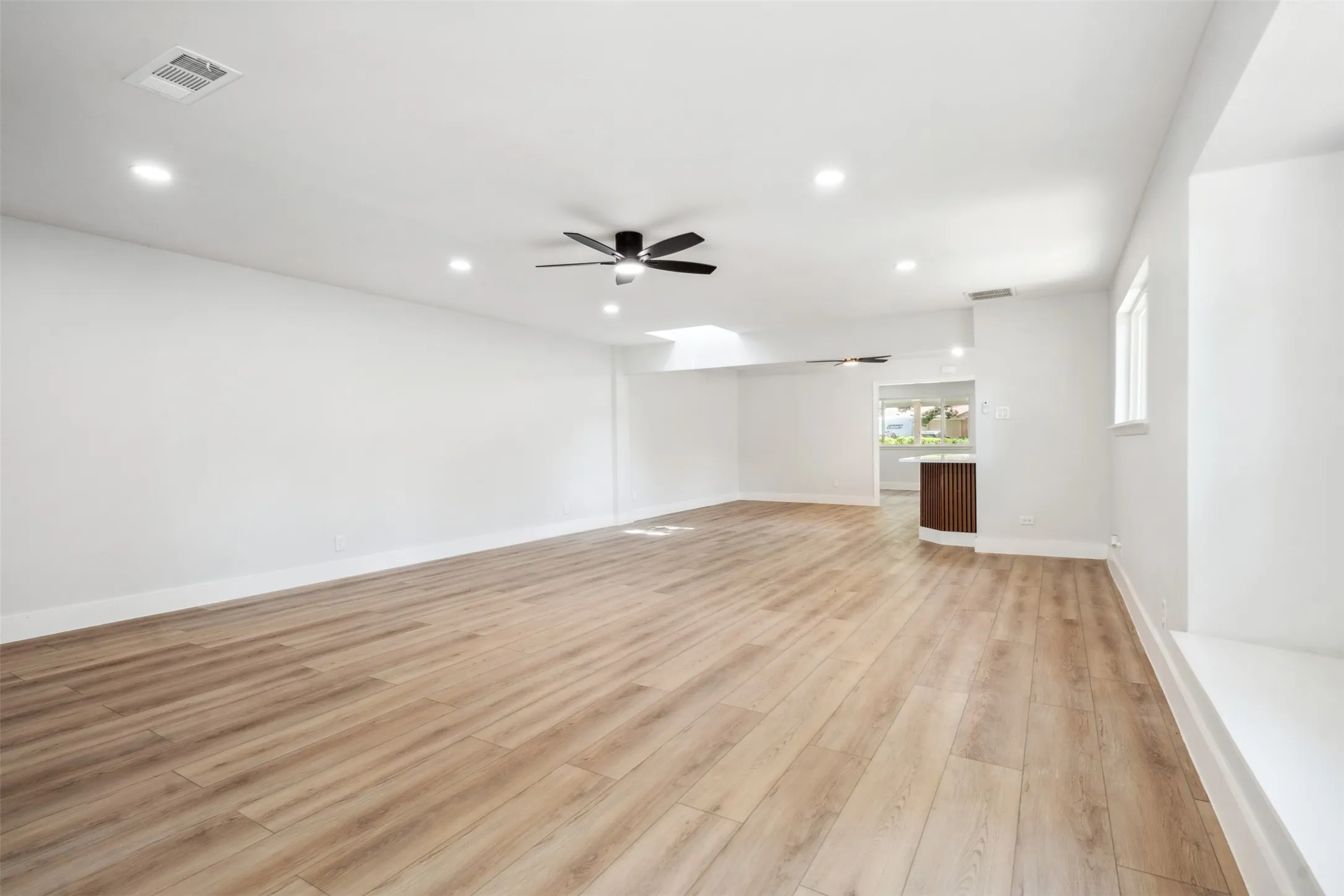 Spacious open-concept room featuring light wood-finish flooring and recessed lighting