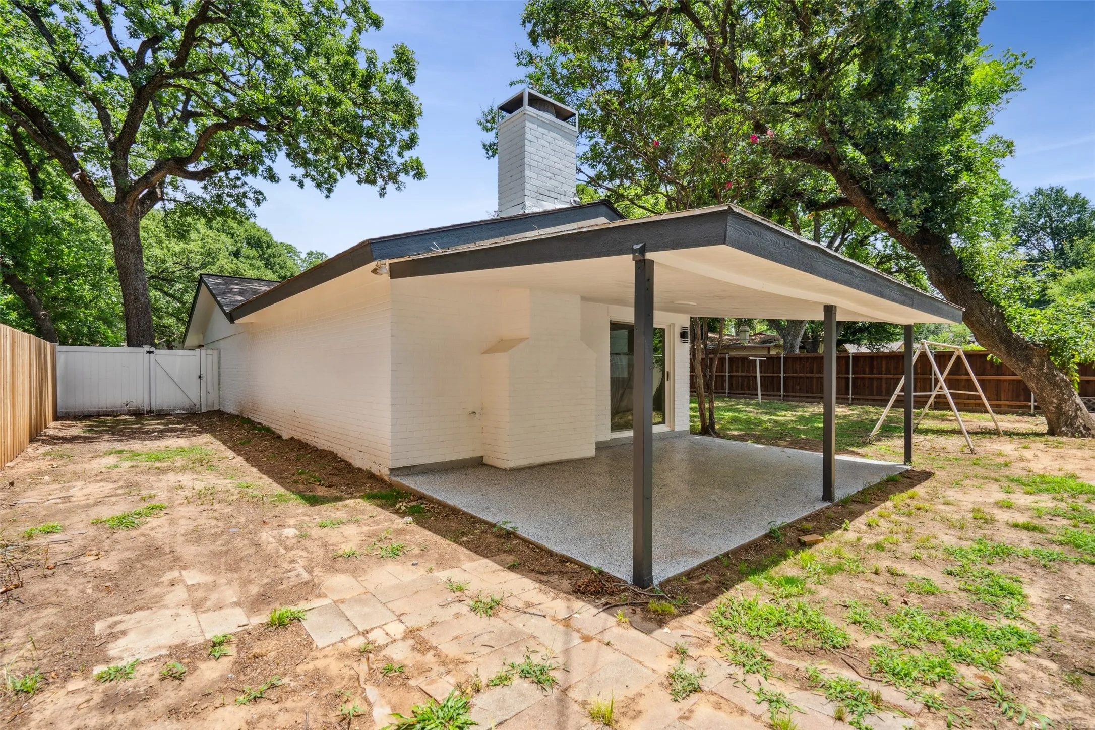 Backyard featuring a covered patio with a speckled concrete surface