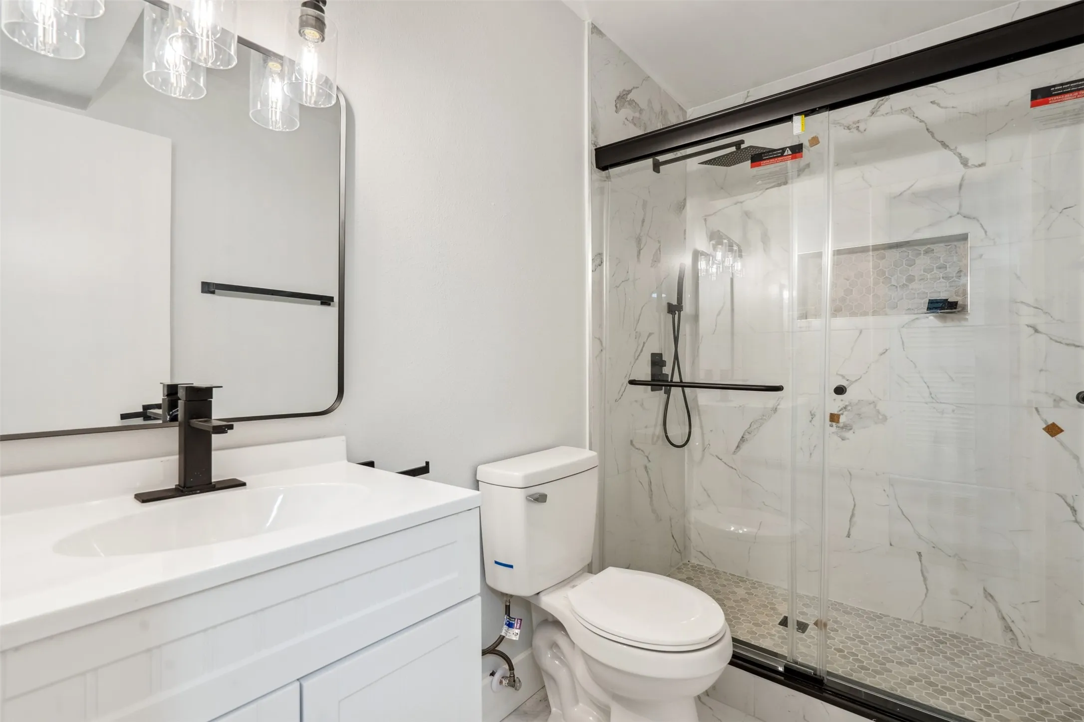 Modern bathroom featuring a white vanity with integrated sink, black-framed mirror, and a black-finish faucet