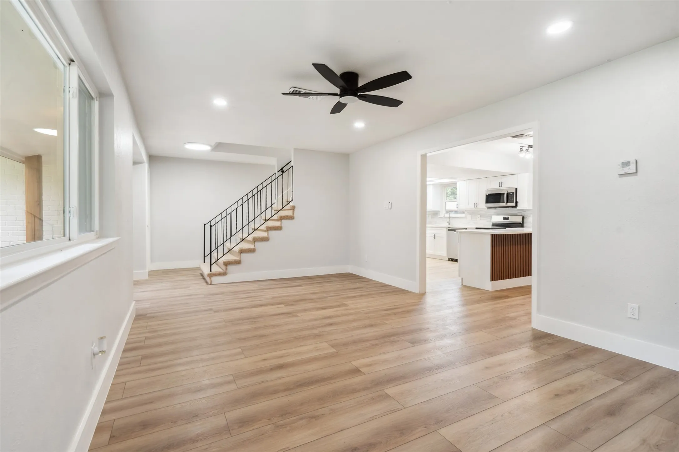 Spacious living area featuring wood-finish flooring, recessed lighting, and a modern ceiling fan